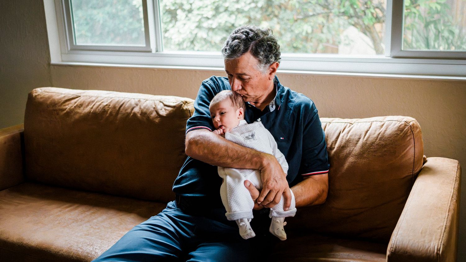 A series of connected photos showing someone holding and cuddling with a small white dog on a brown leather couch.