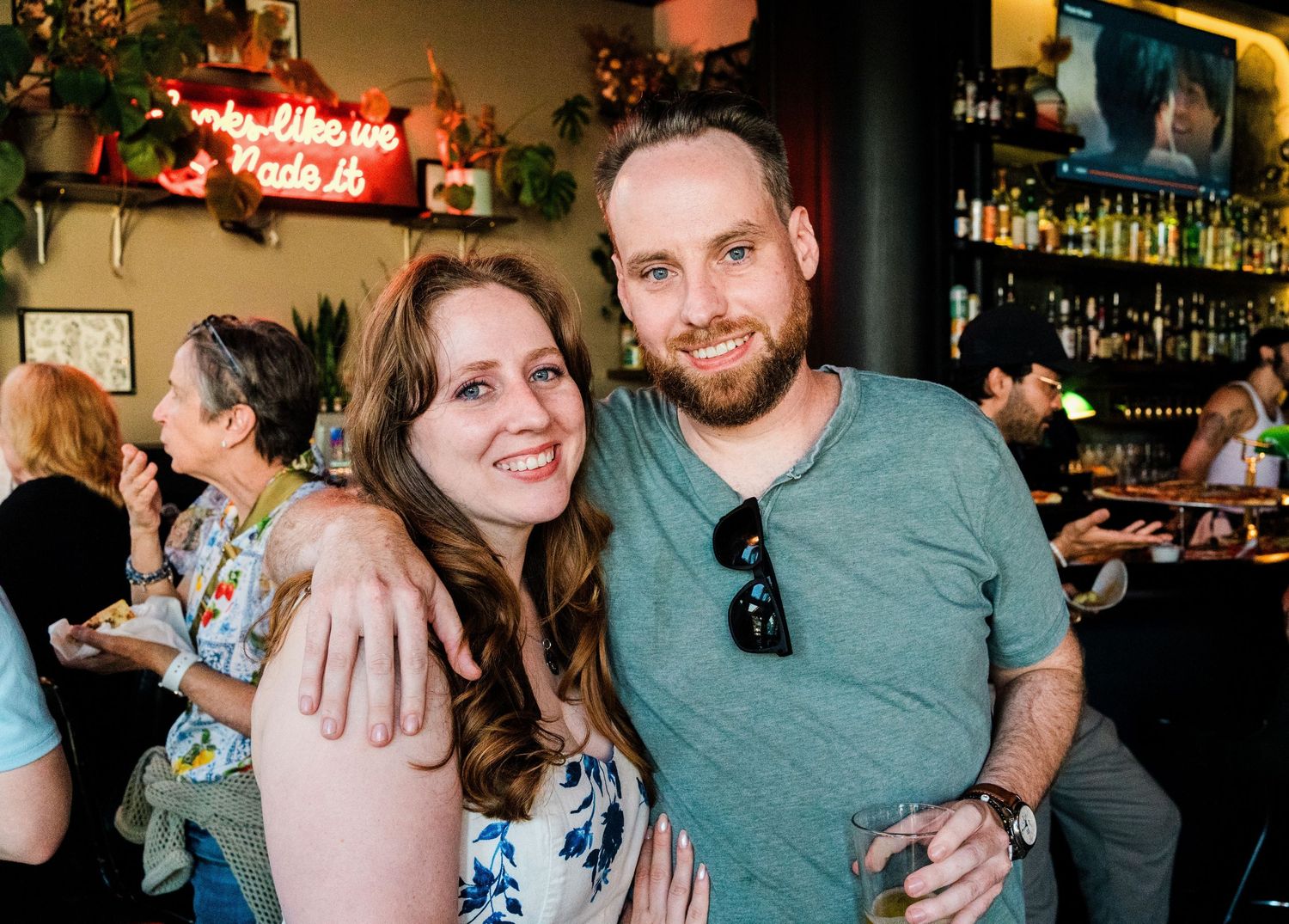Newly engaged couple celebrating at a casual bar gathering with warm lighting.