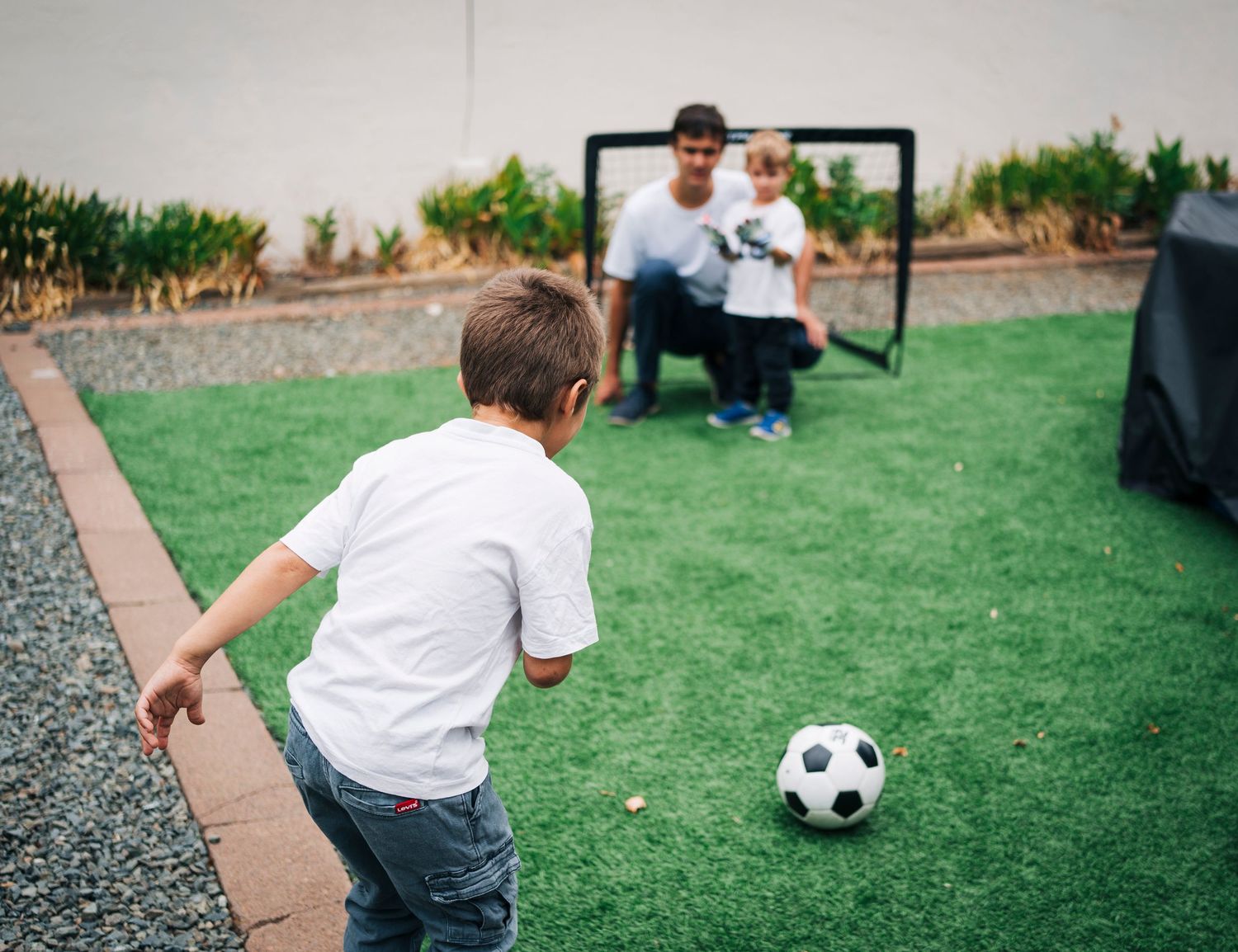 A sequence of action shots showing a child in a white shirt playing soccer on a grassy field.