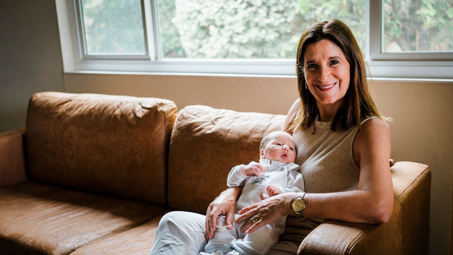A progression of photos shows a newborn baby being placed on a brown couch for a photoshoot.