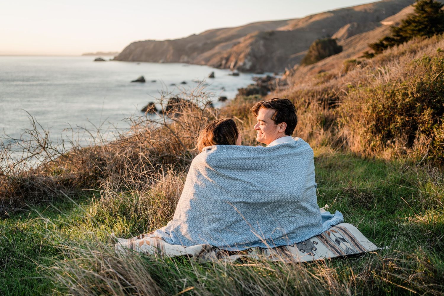 Scenic coastal cliffside trail at sunset with golden light illuminating the rugged California coastline.