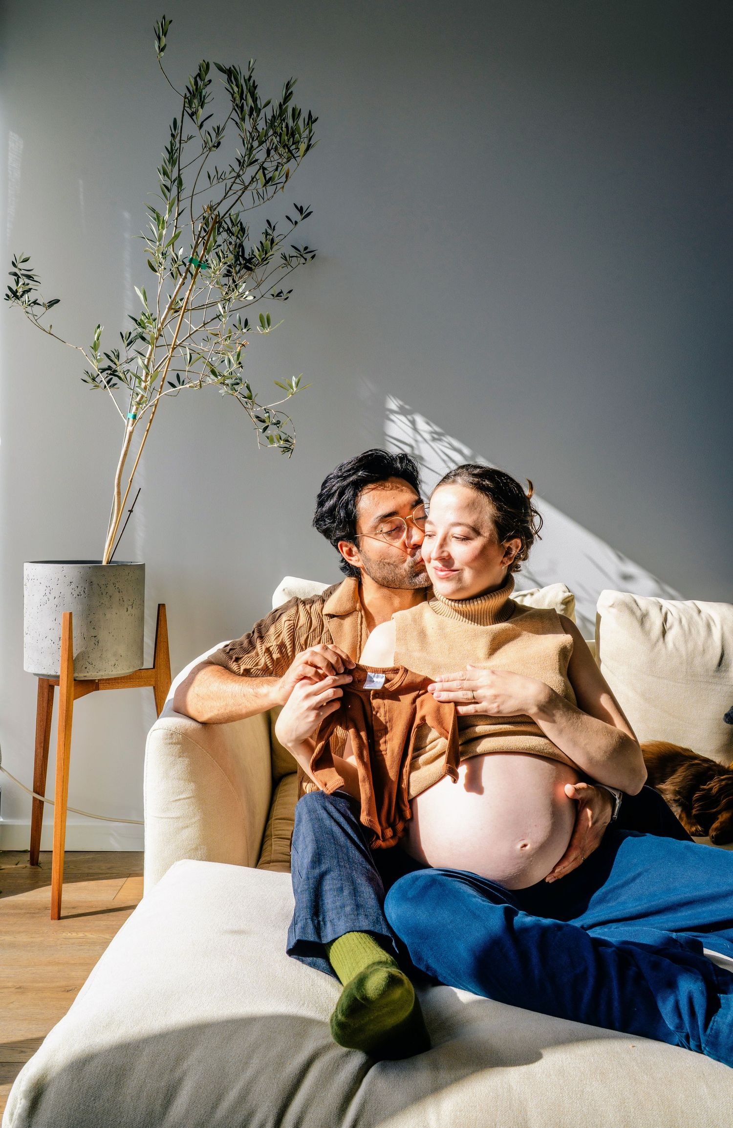 A series of intimate maternity photos showing a couple resting together with greenery in the background.