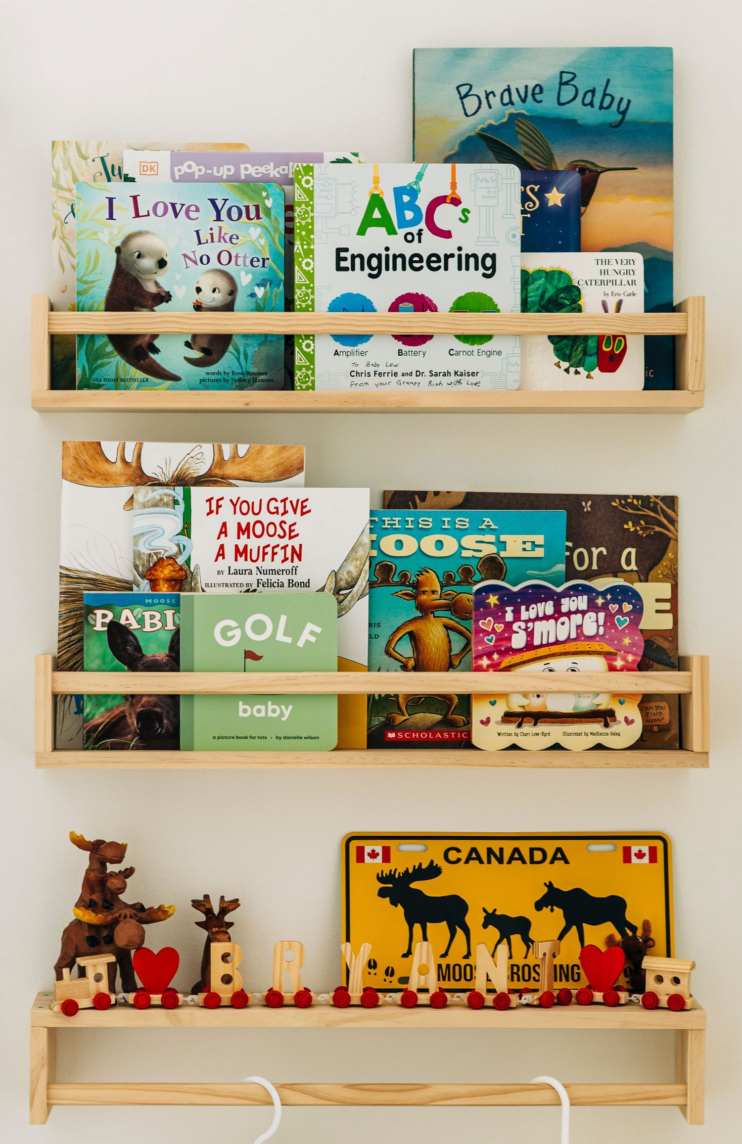 Wooden wall shelves displaying colorful children's books and decorative woodland animal silhouettes.