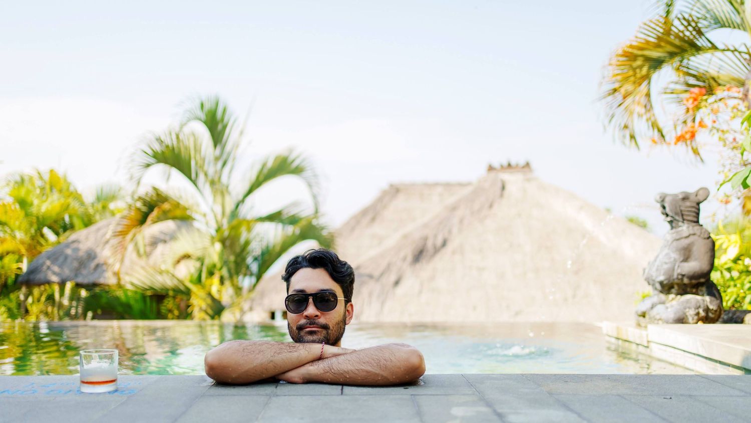 Person relaxing by tropical palm trees and beach scenery.