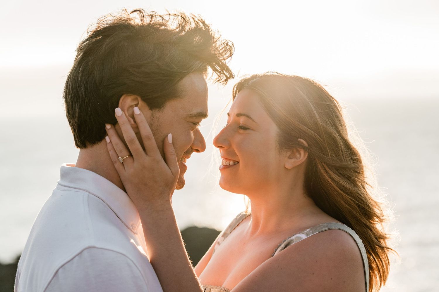 A couple shares an intimate moment at sunset on the beach, silhouetted against the warm golden light.