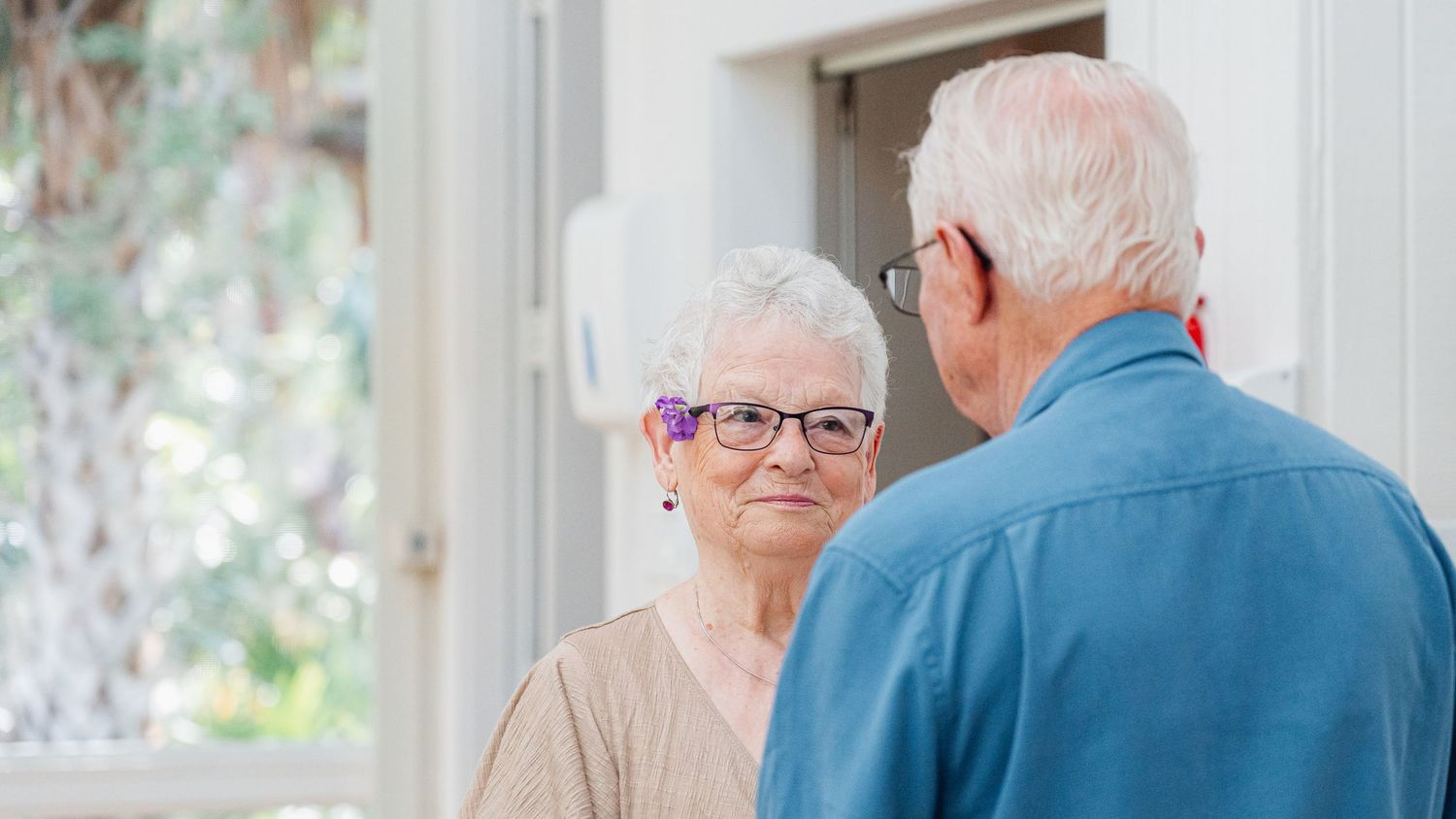 Senior adults sitting in a bright sunlit room during a social gathering or meeting.