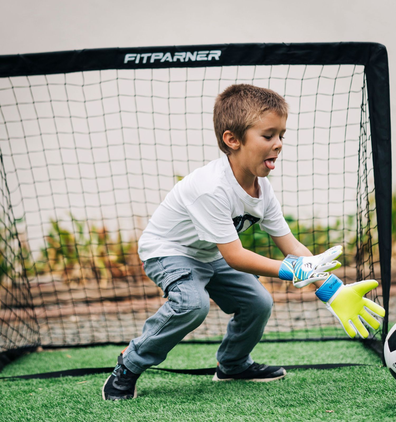 Young soccer goalie practicing diving saves on artificial turf with training equipment.