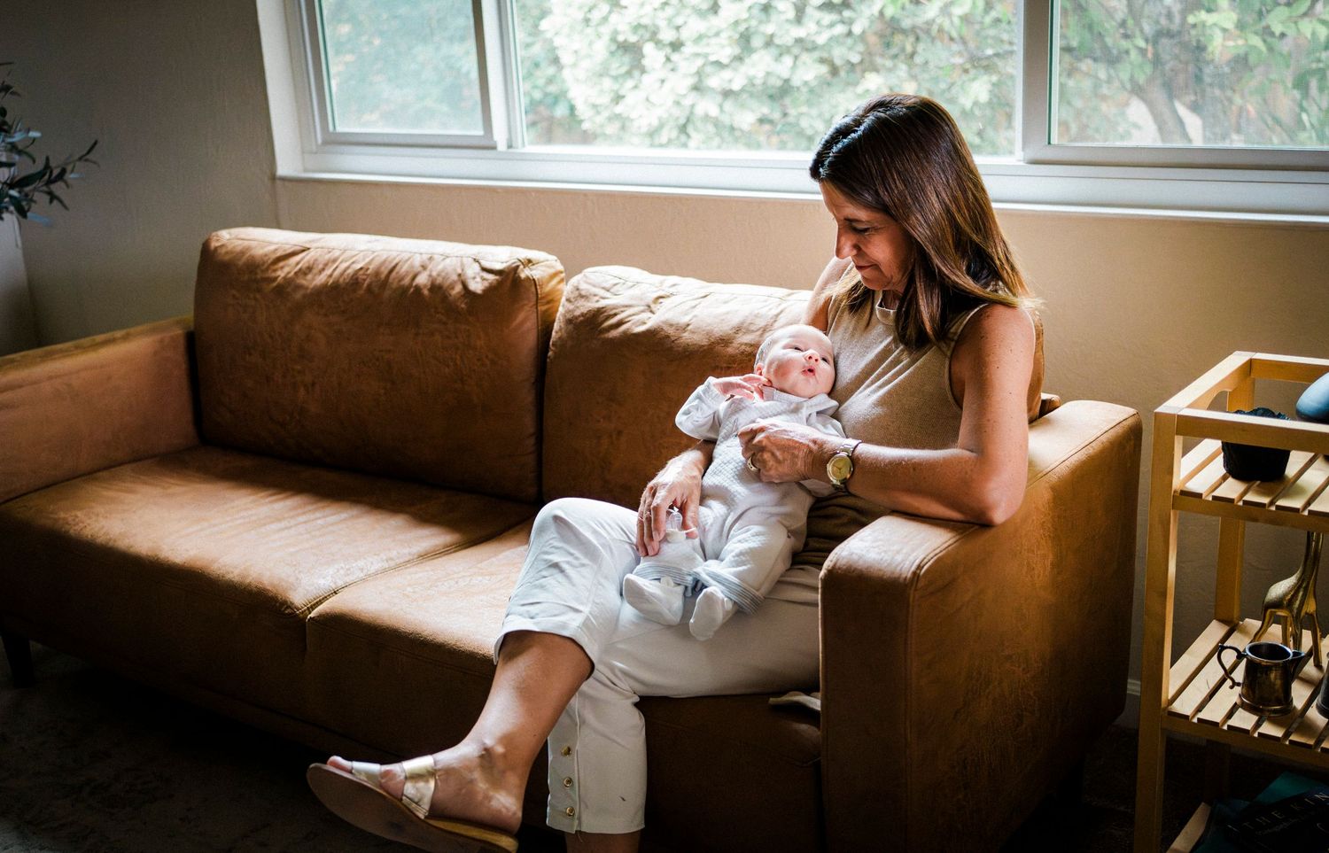 Intimate lifestyle photo session showing tender moments on a couch in natural window light.