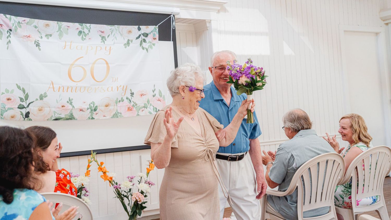 A wedding vow renewal with elderly bride celebrating down the aisle lined with floral decorations and family guests.