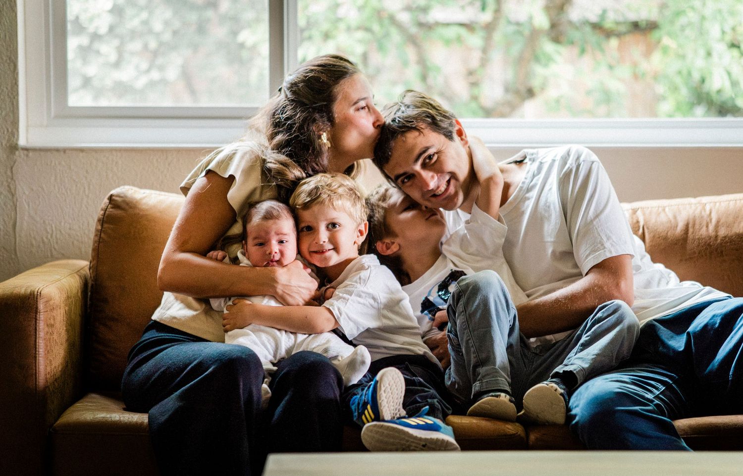 A loving family relaxes and shares tender moments together on a cozy couch at home.