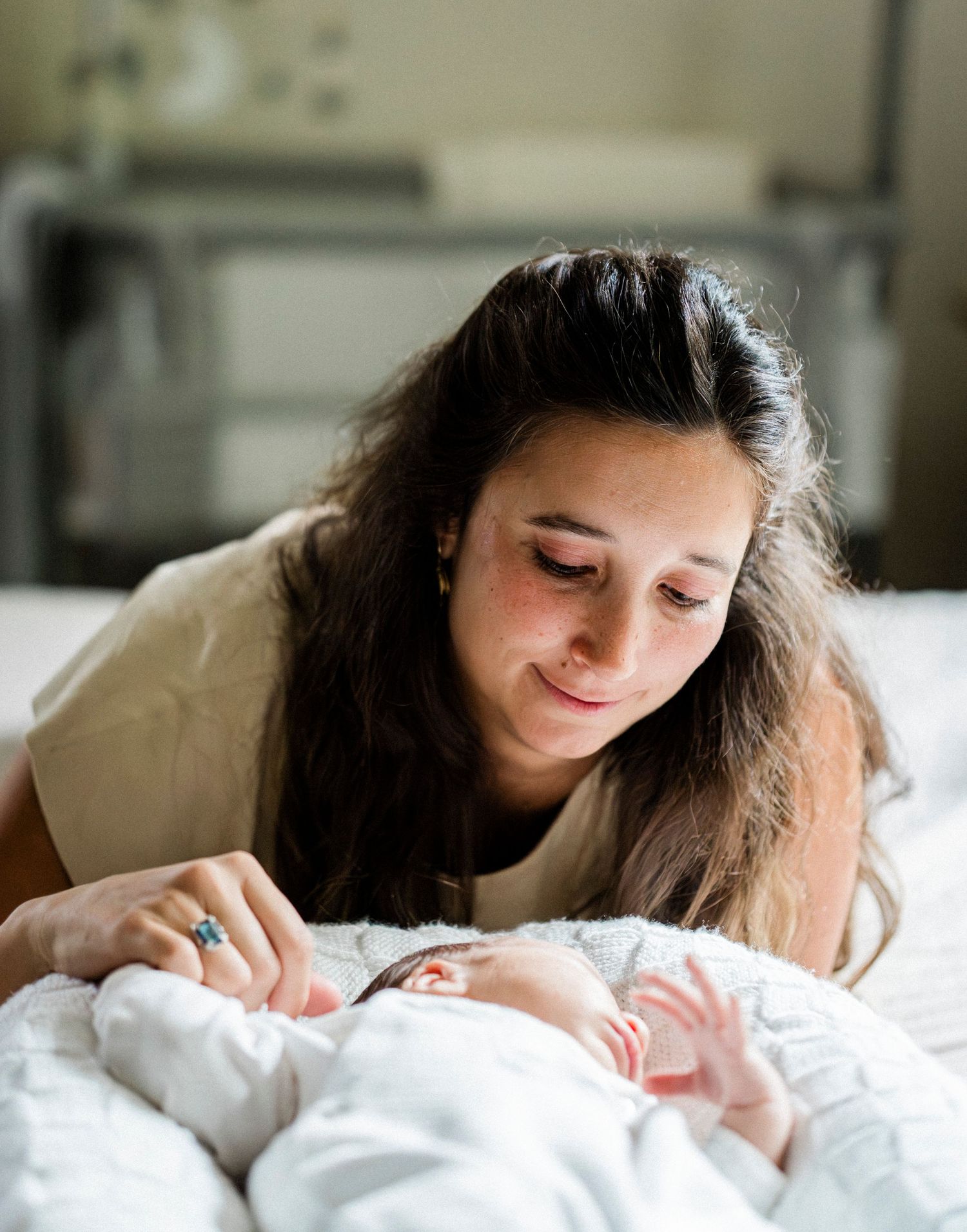 A series of intimate moments captured on a white bed showing gentle interaction with a baby.