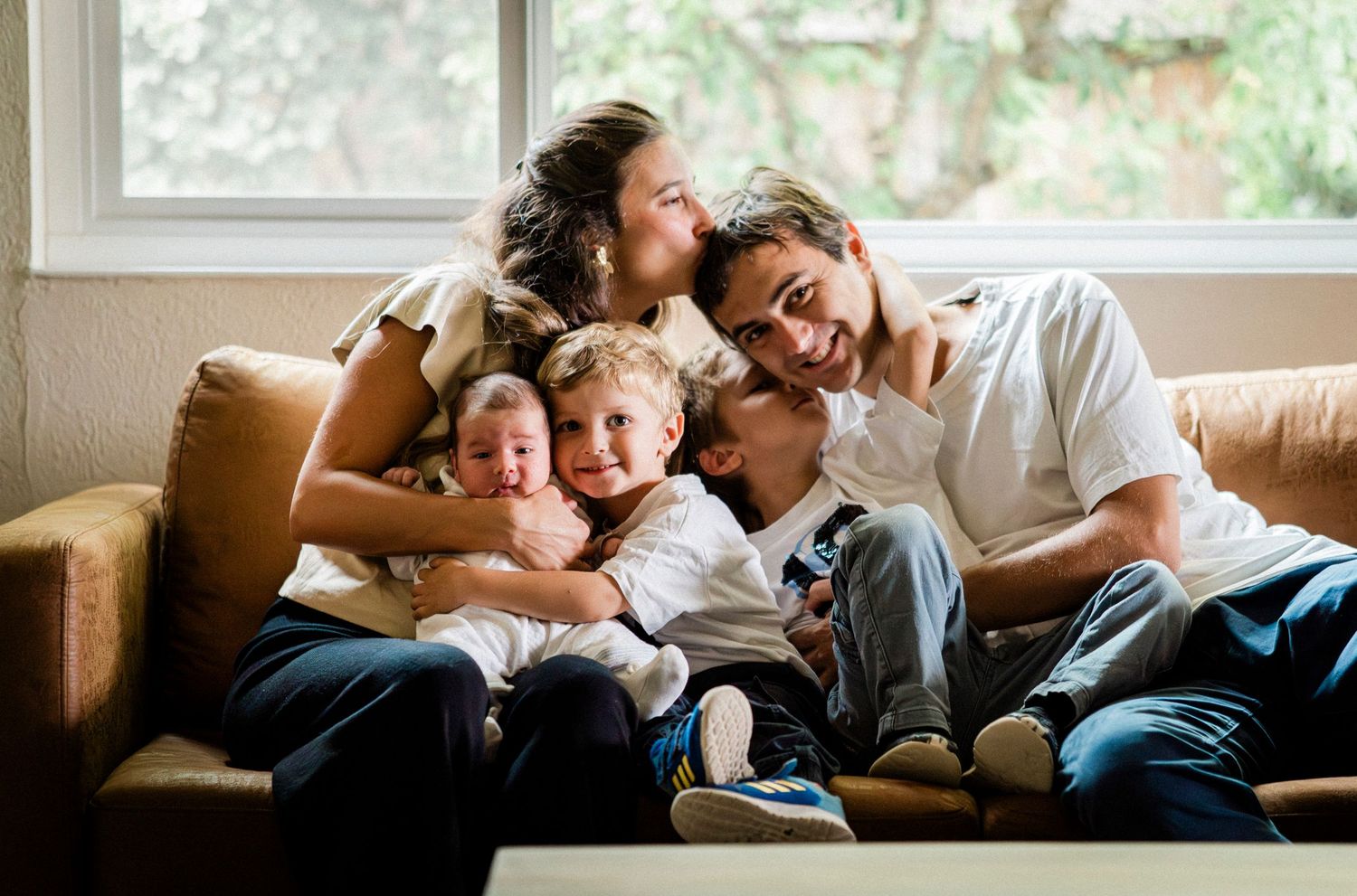 Family members relaxing together on a comfortable couch in natural window light.