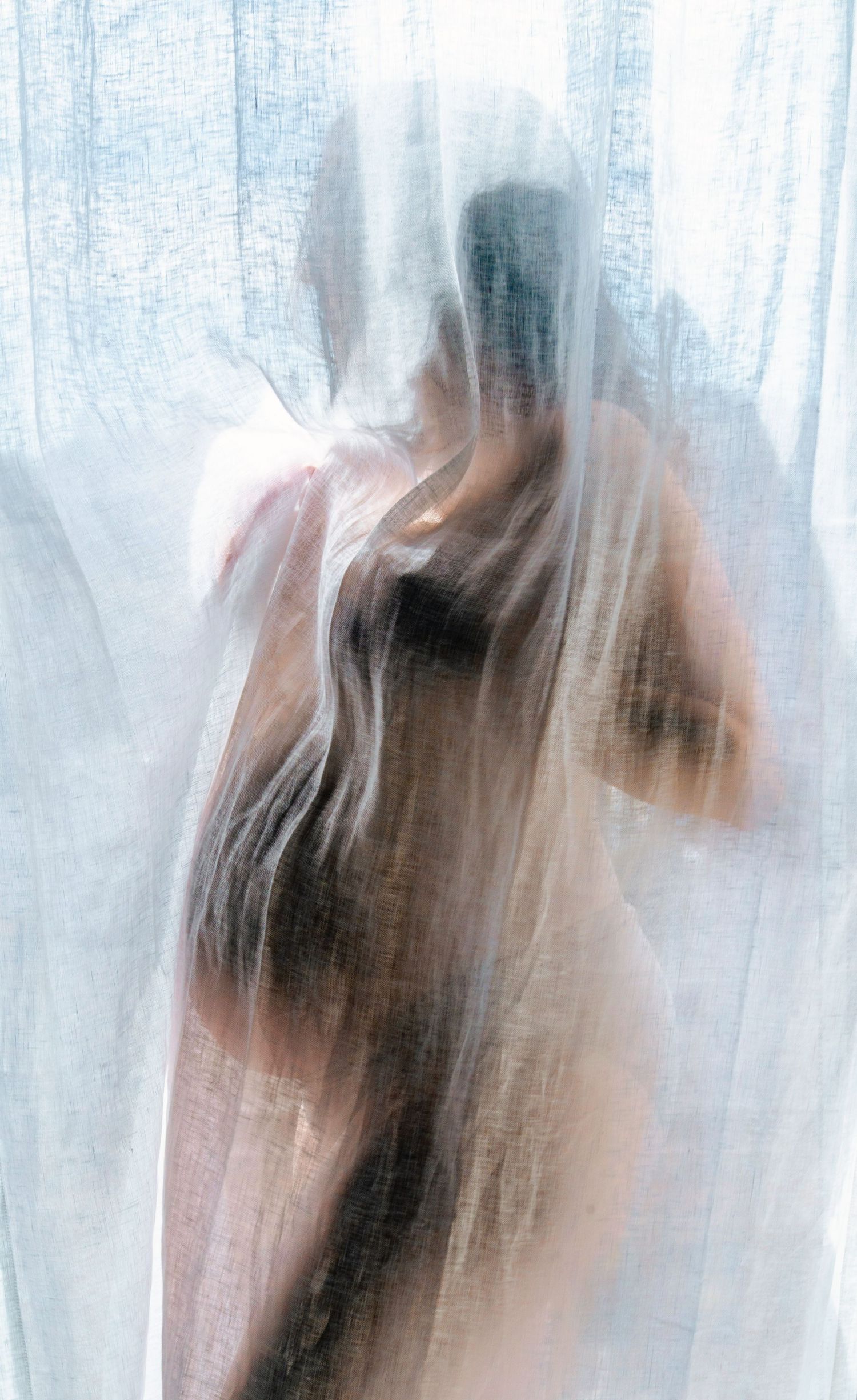 Abstract maternity silhouettes photographed through sheer white curtain.