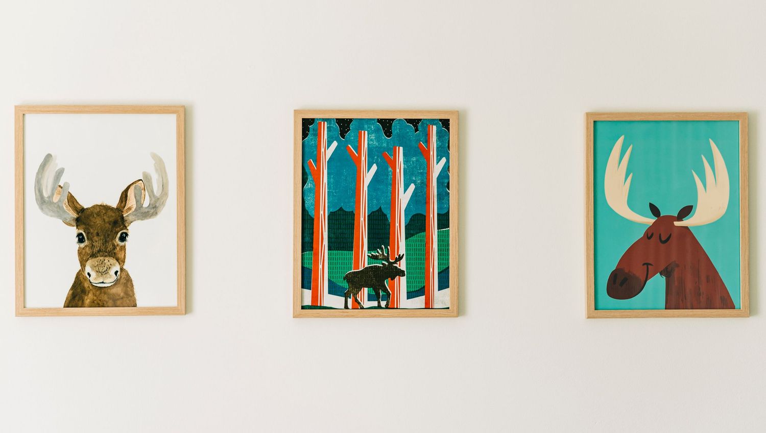 Collection of framed woodland animal art prints arranged on white wall in a baby nursery