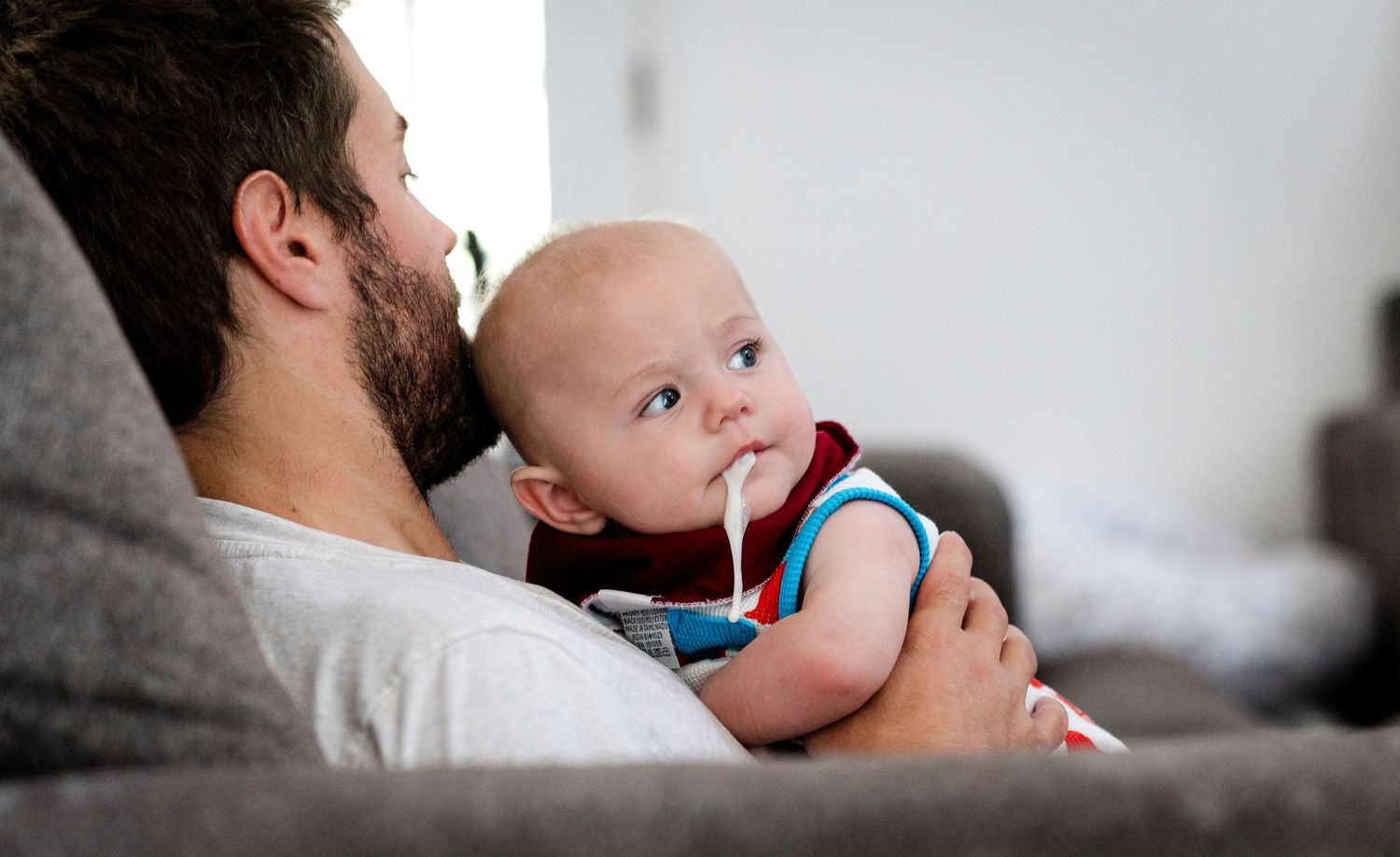 Intimate lifestyle moments capturing a baby spiting up on his dad.