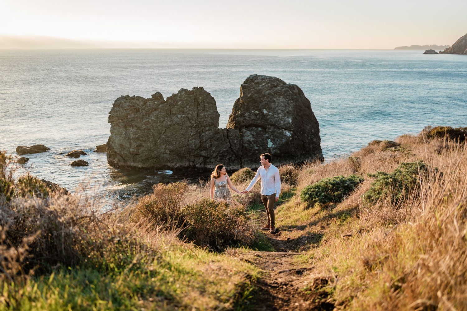 Scenic coastal landscape with rugged cliffs, golden grass, and turquoise ocean waters along the Pacific coastline.