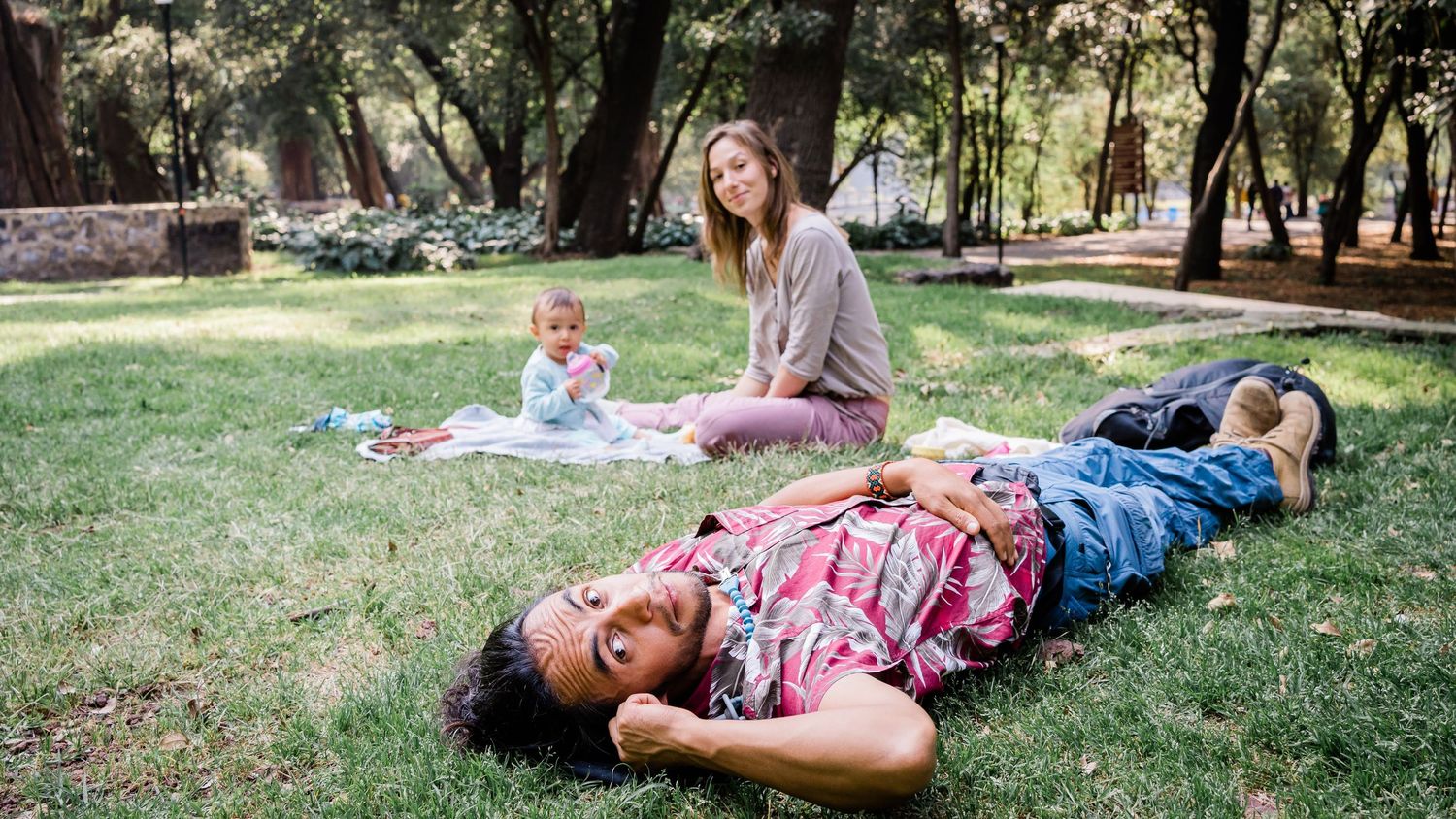 Group enjoying a relaxed afternoon picnic on grass under shady trees.