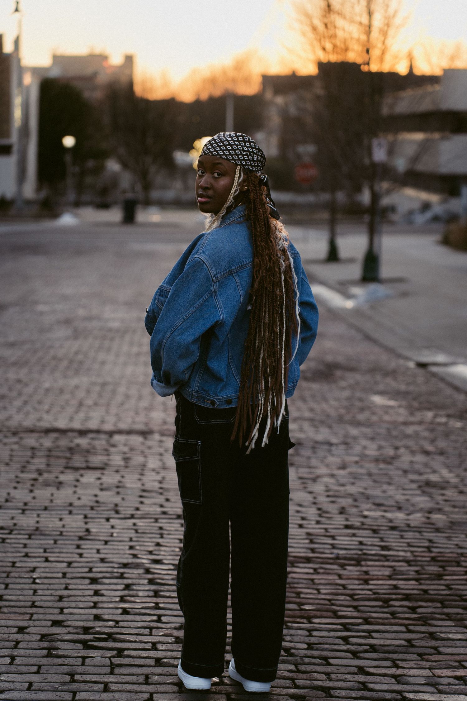 Portrait image of a woman looking over her shoulder at golden hour in an urban setting