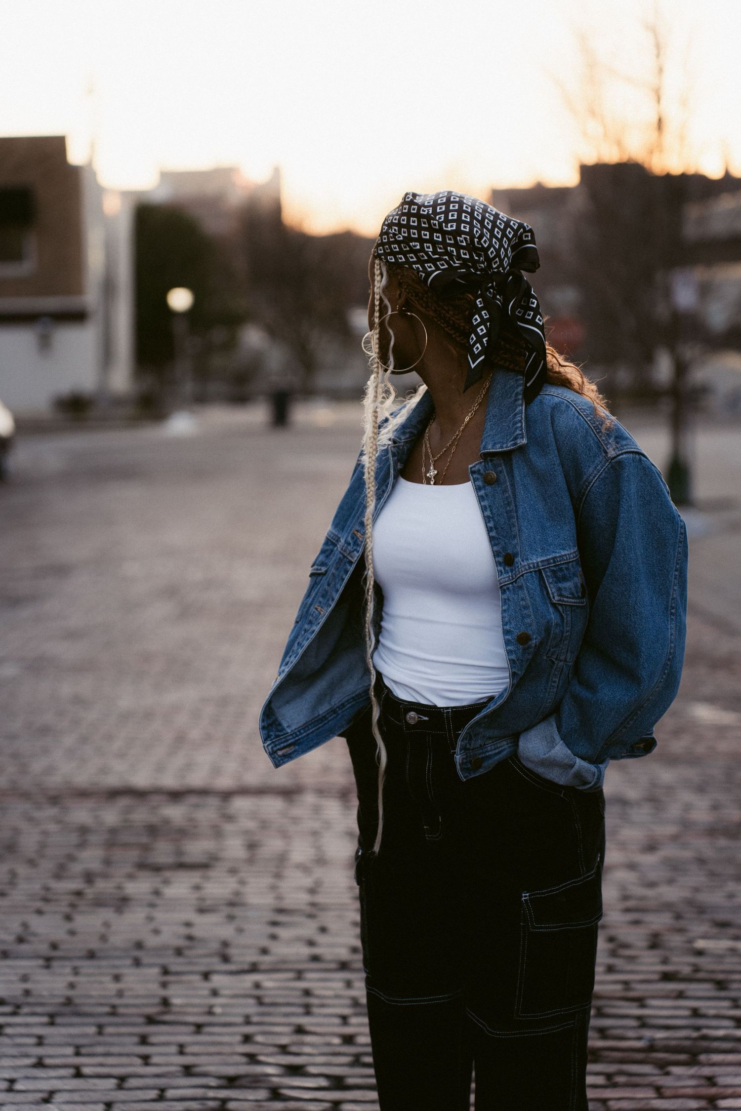 Portrait image of a woman looking over her shoulder away from the camera at golden hour in an urban setting