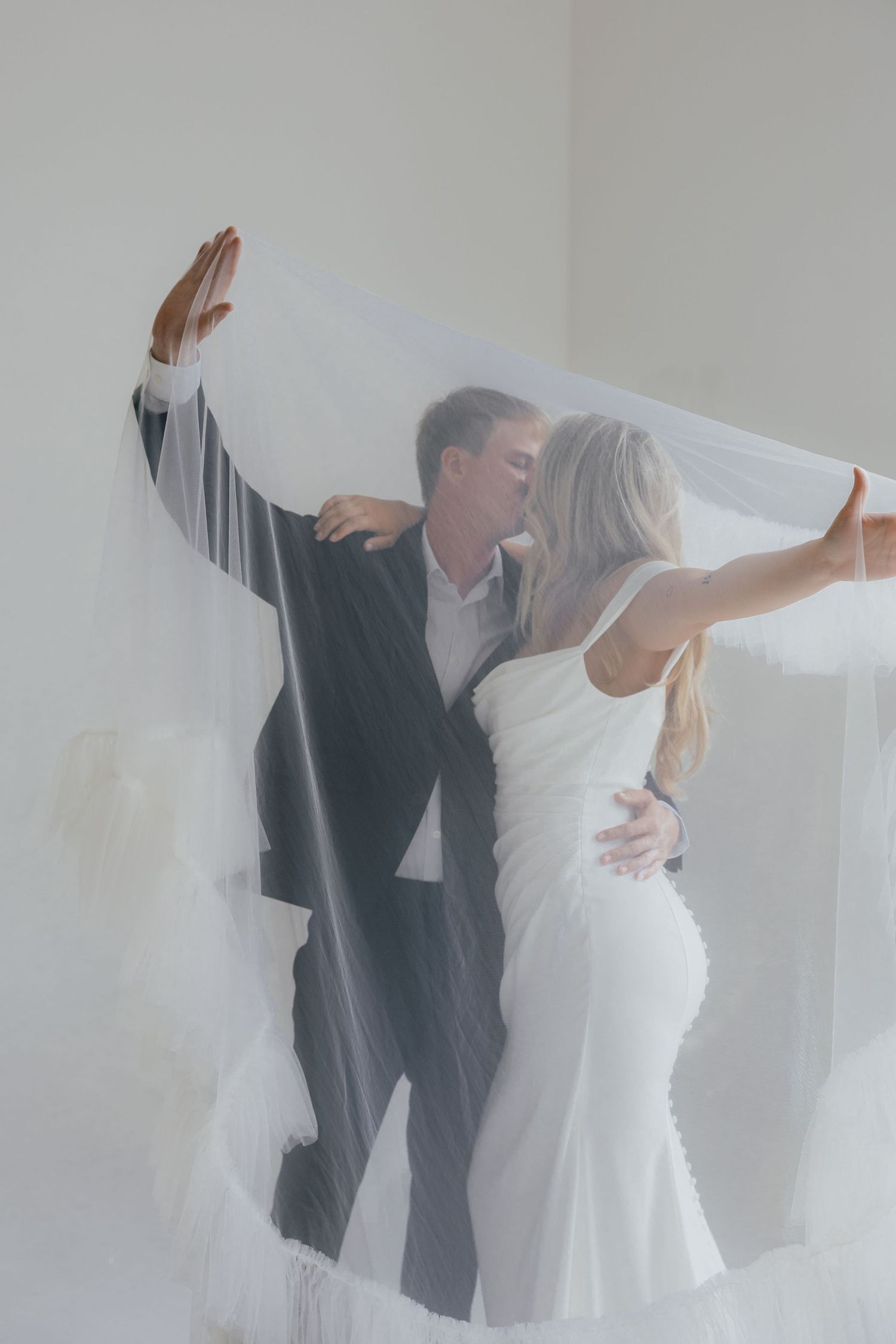 A couple in wedding attire dance together against a white backdrop in an artistic photo sequence.