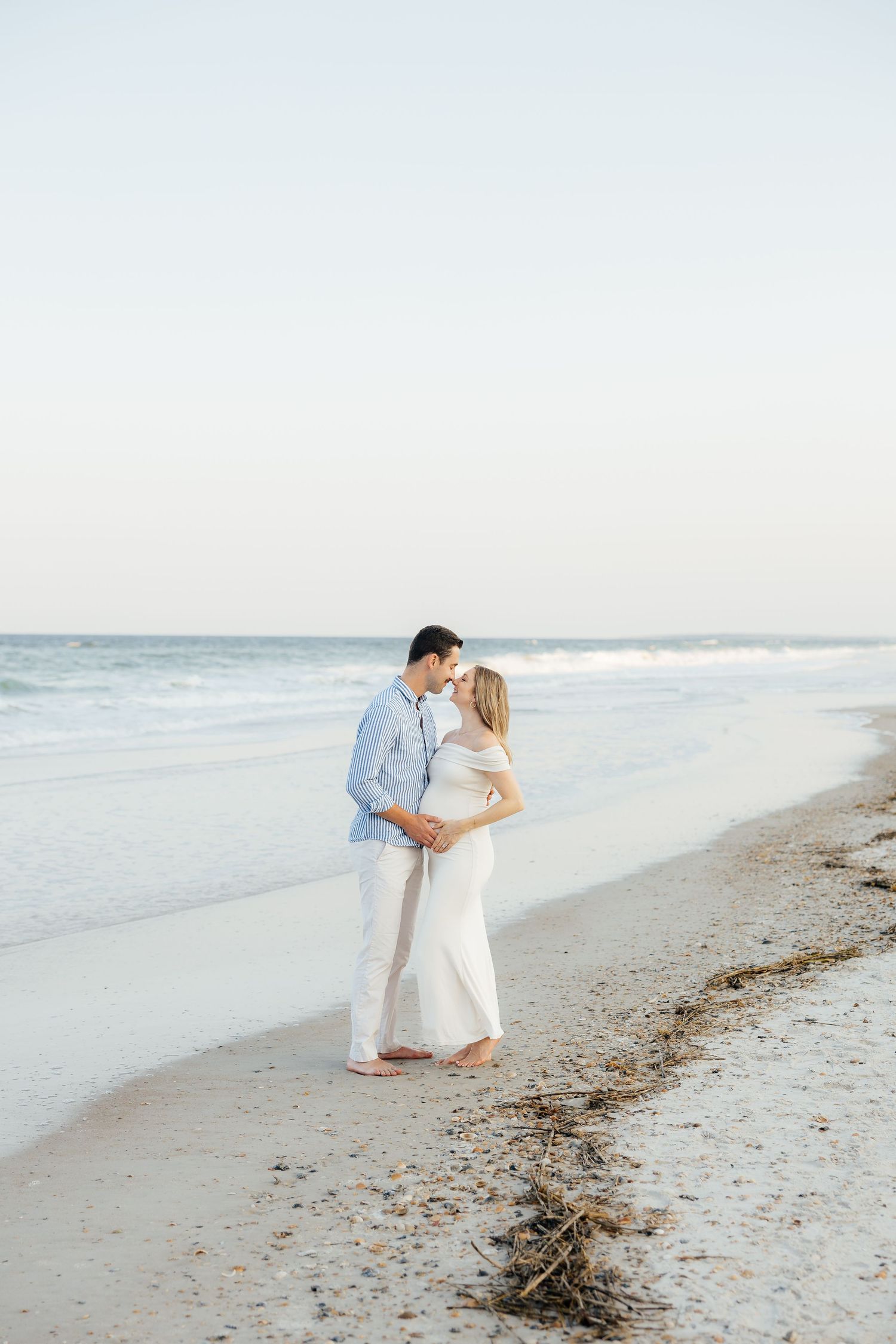 A romantic couple shares tender moments while walking along a peaceful beach at sunset.