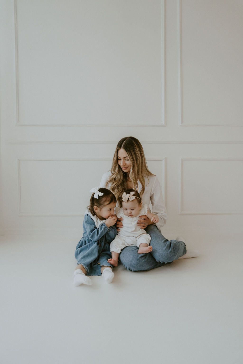 An intimate family portrait in a minimalist white studio setting.