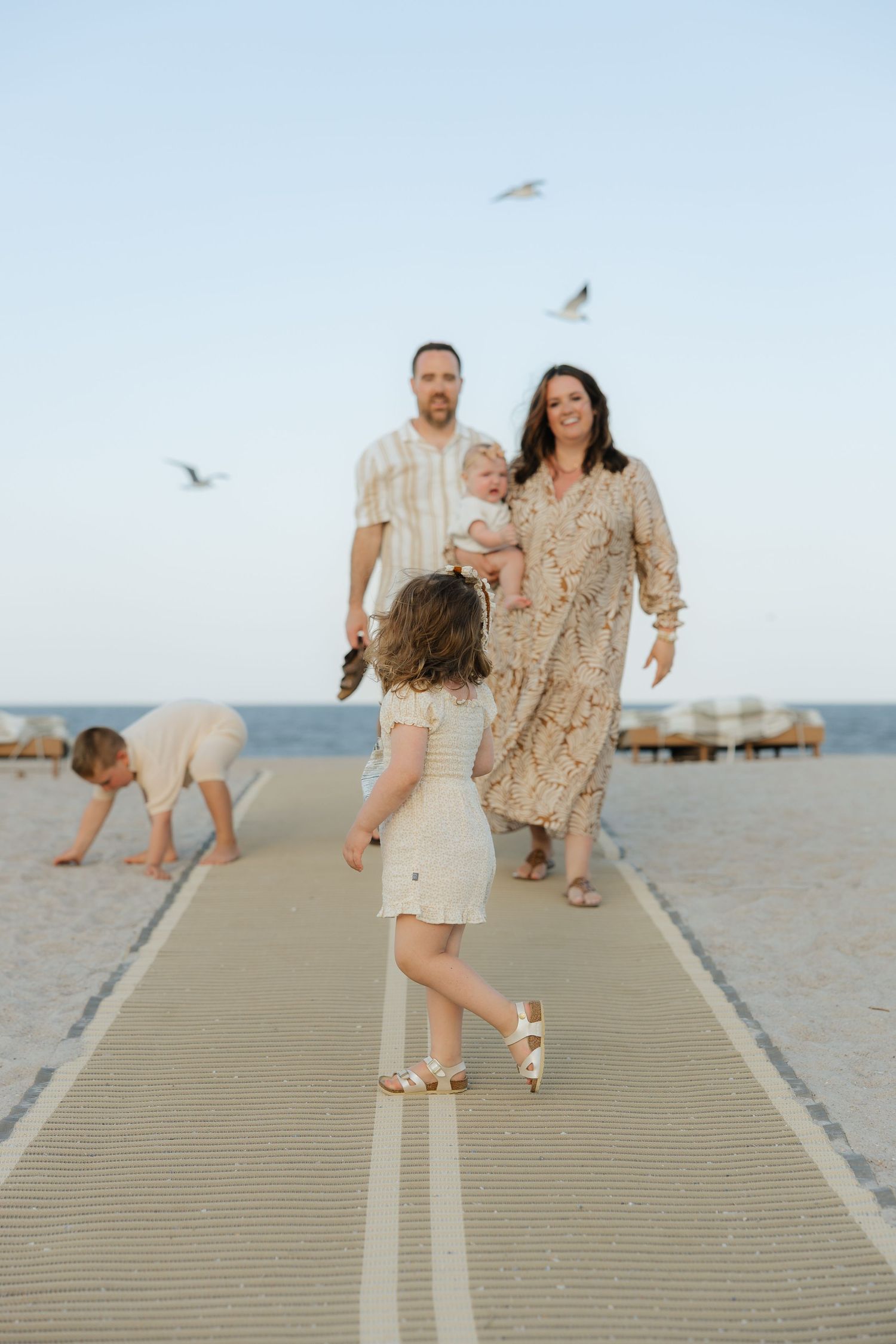 A family walks along a beach boardwalk with seabirds flying overhead at Omni Amelia Island Resort & Spa.