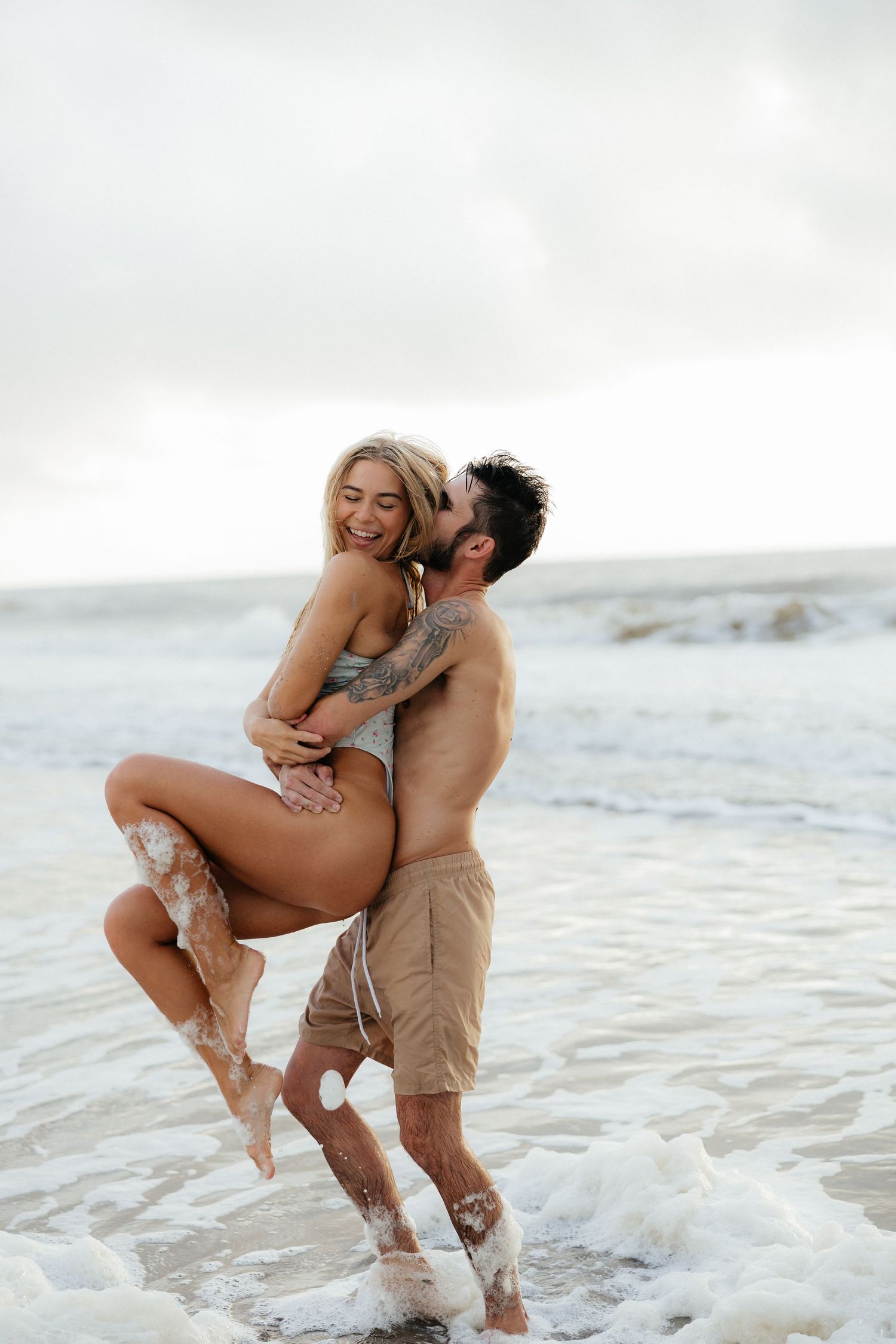 A joyful couple embracing and laughing together in the ocean surf.