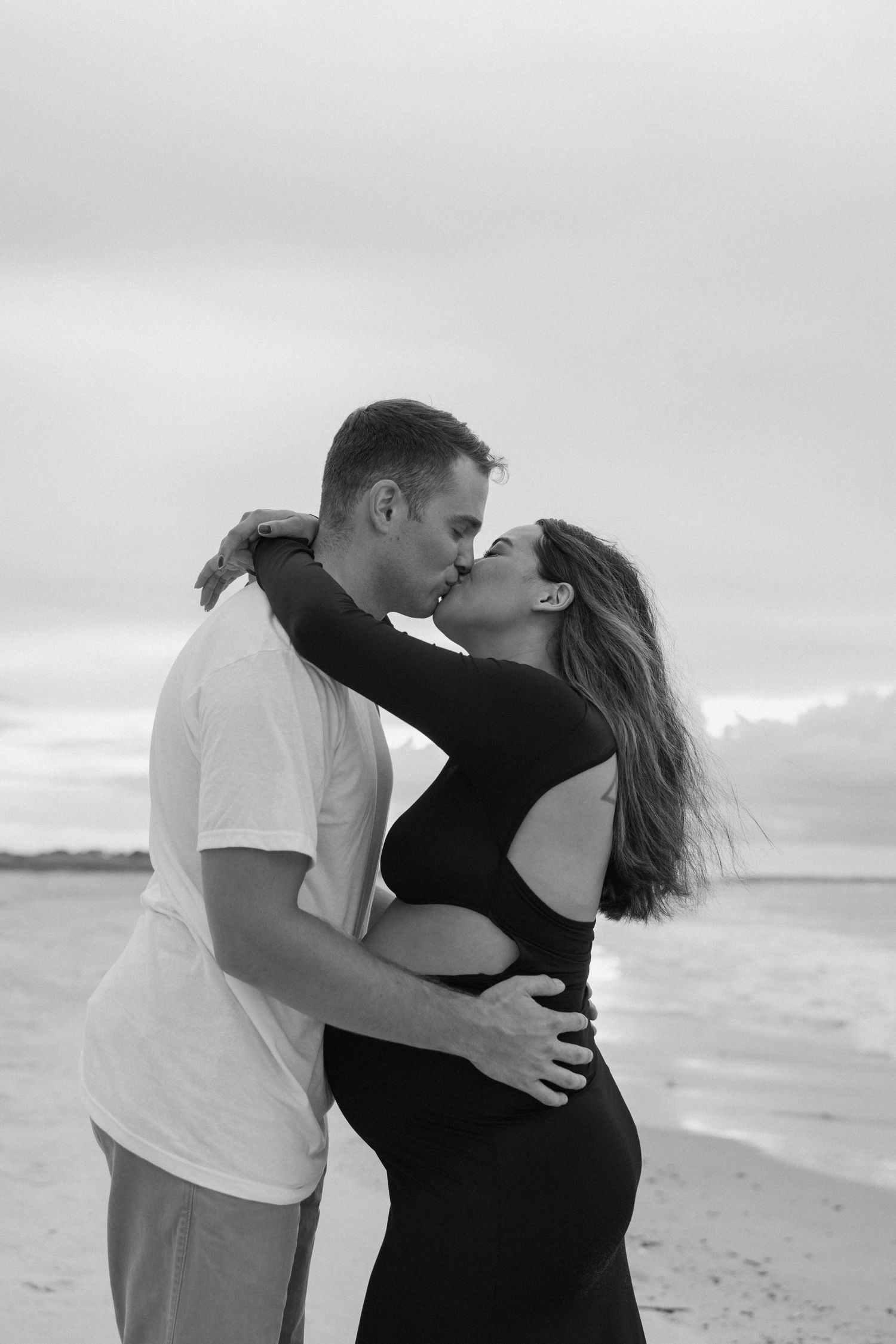 Intimate black and white photo of couple on cloudy Fort Clinch State Park beach.