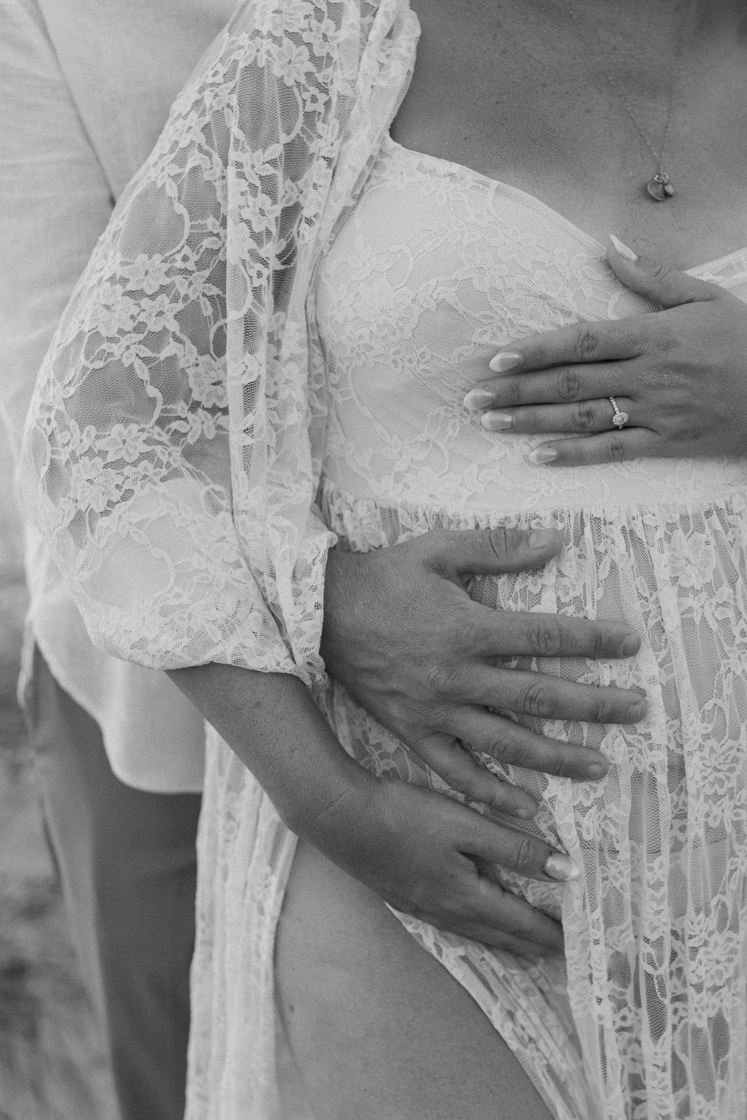 Close-up of hands tenderly embracing through delicate white lace fabric.