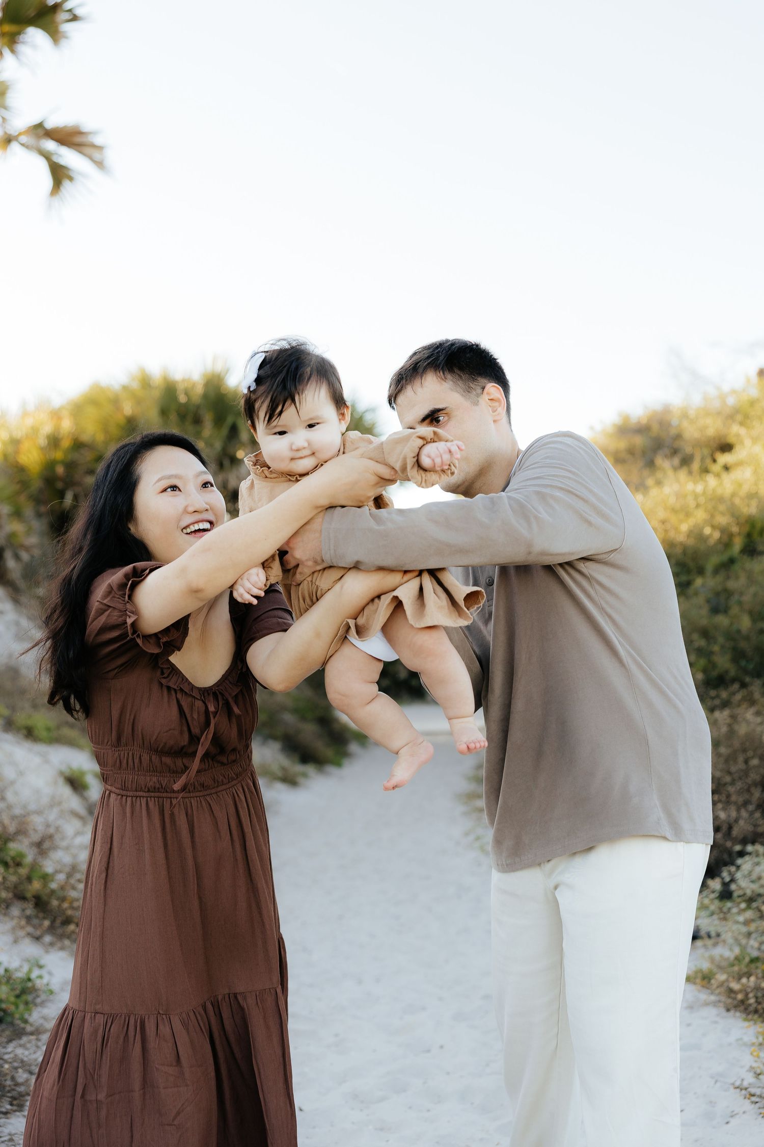 A playful family photo sequence at the beach shows parents swinging and cuddling their baby in warm sunset lighting.