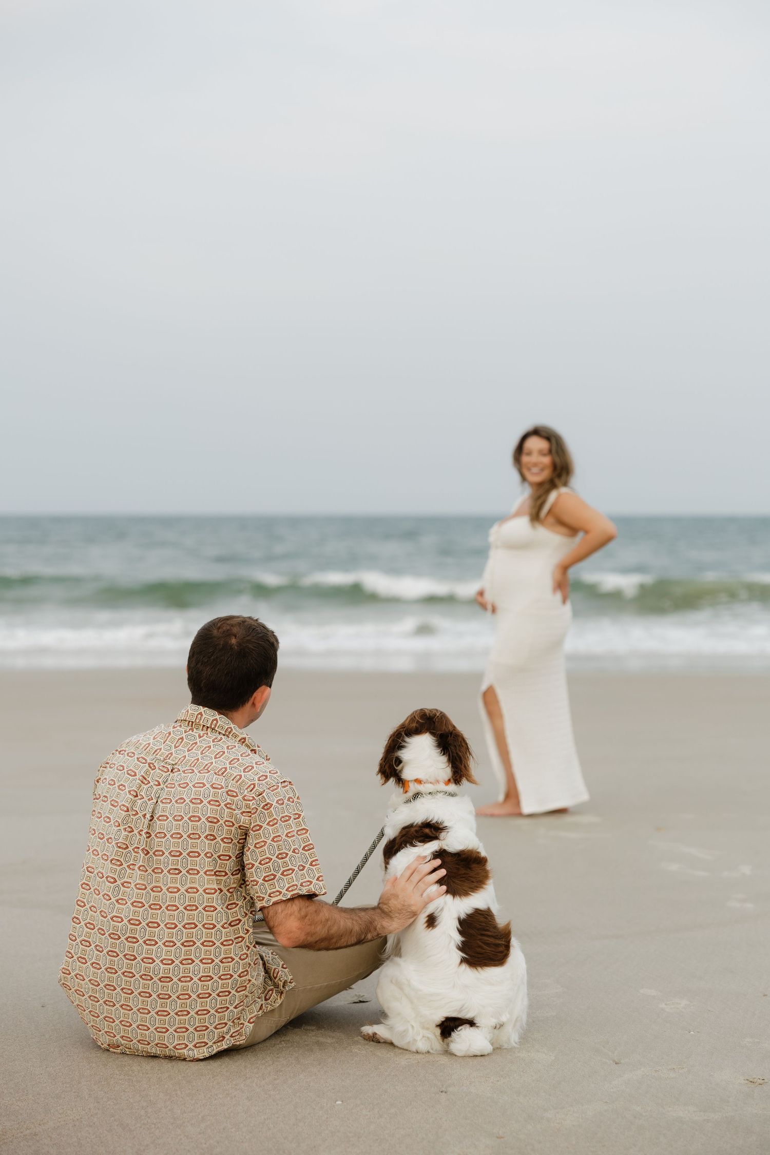 Dog joins couple for romantic beach photos at sunset.