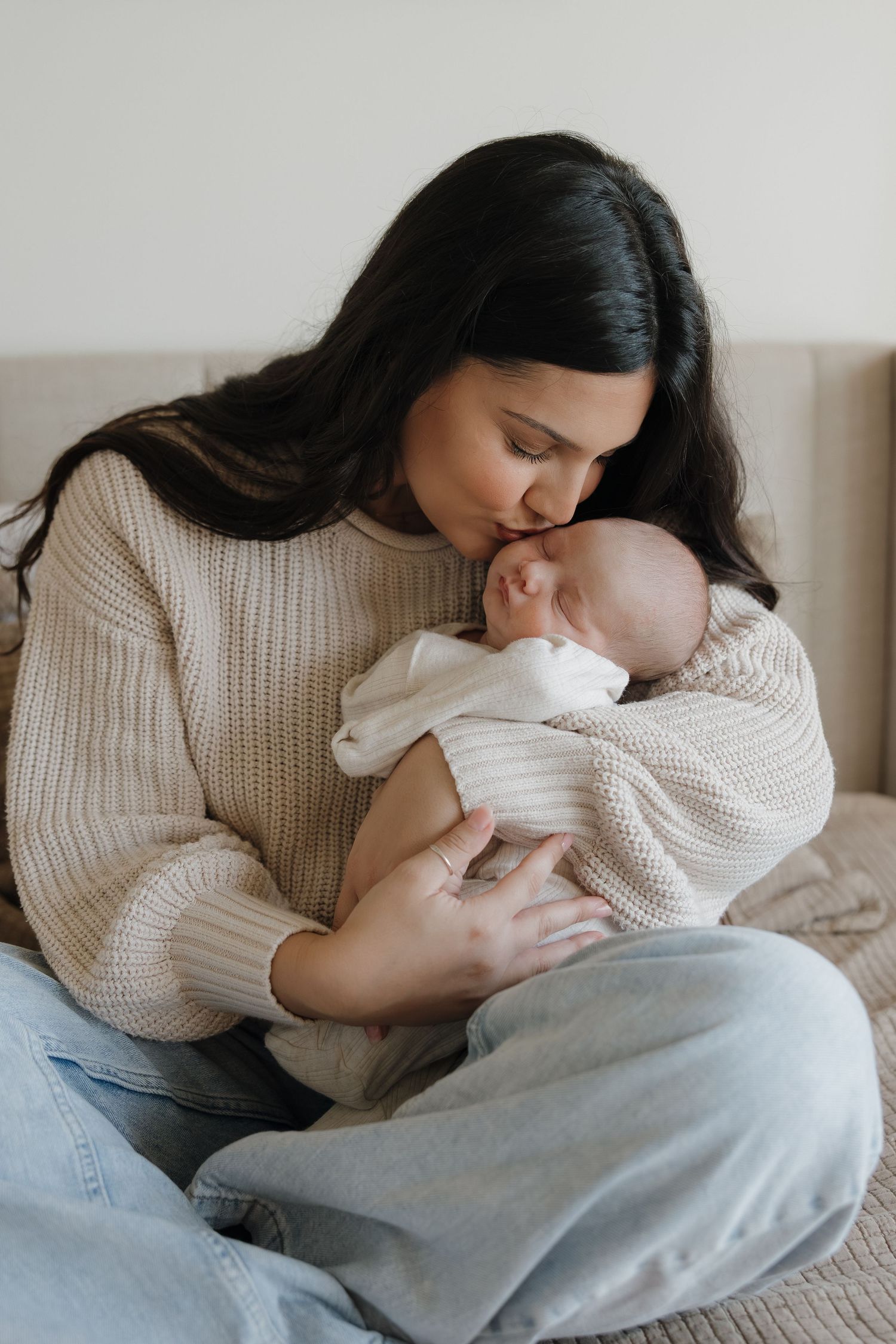 An intimate moment of mother and baby bonding on a comfortable couch in natural light.