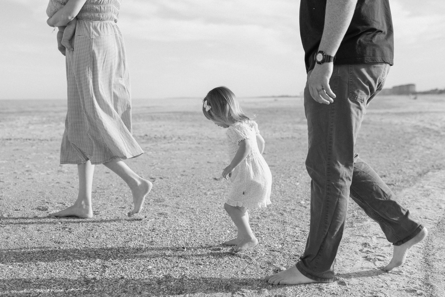 Black and white photo of family walking together on sandy path.