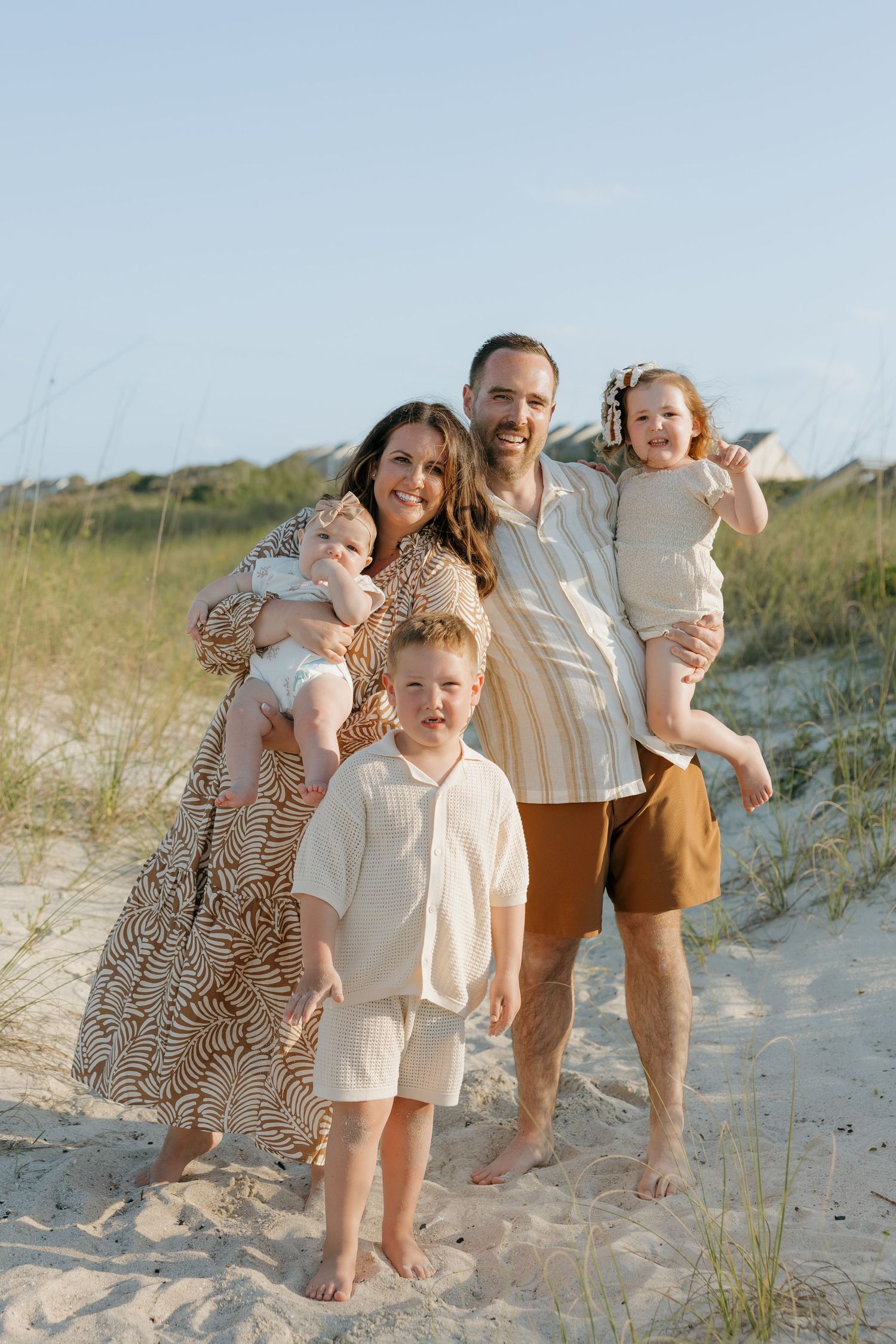 A family poses together for family photography session on sandy dunes during golden hour at Omni Amelia Island Resort & Spa.