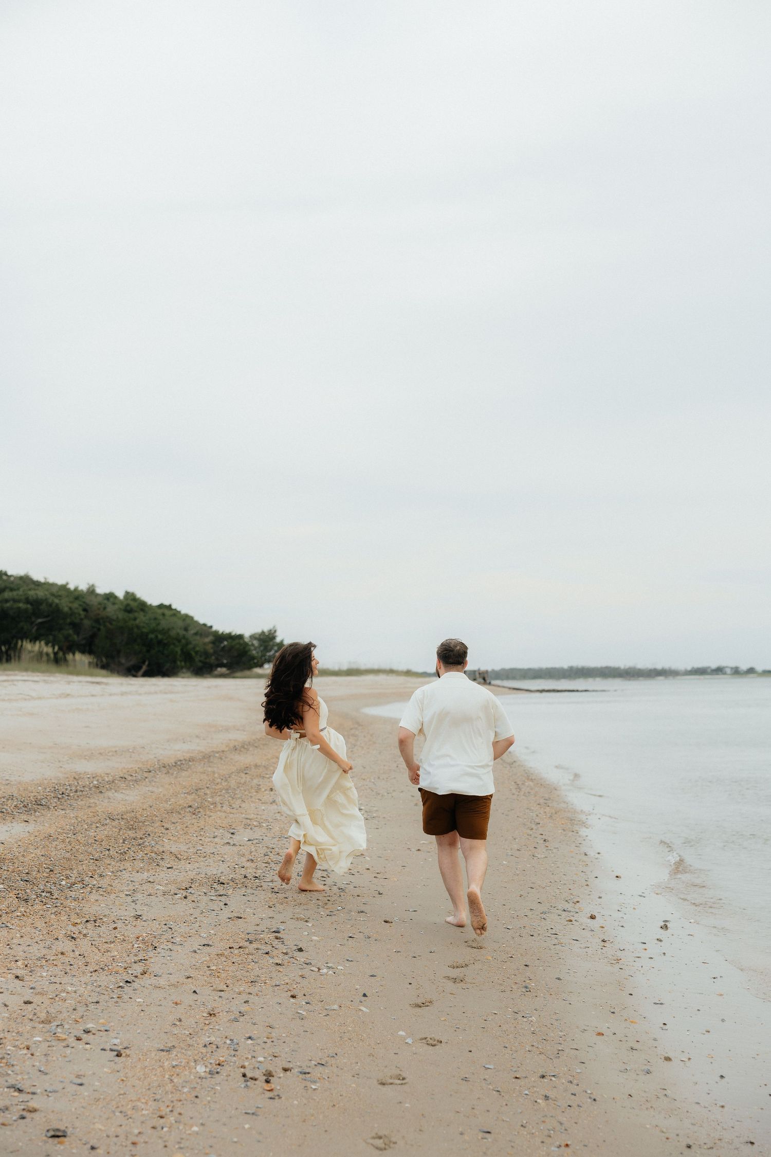 A couple running along a Fort Clinch State Park beach during an overcast day