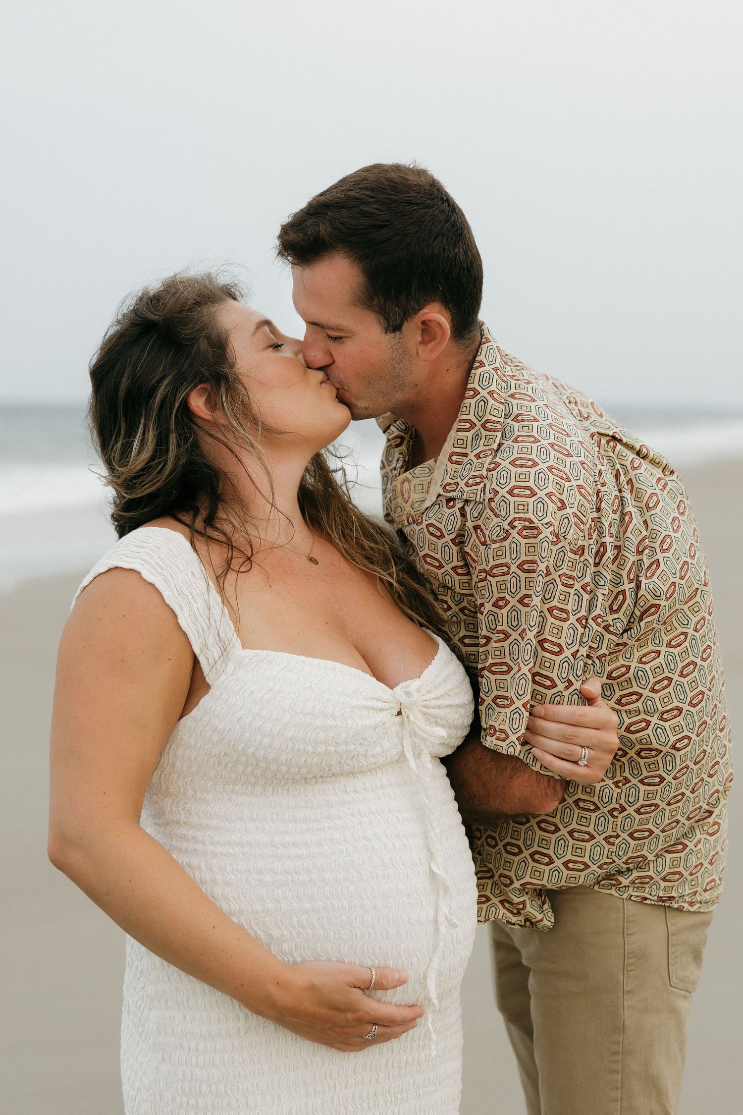 Romantic moment shared between couple in casual attire on sandy beach.