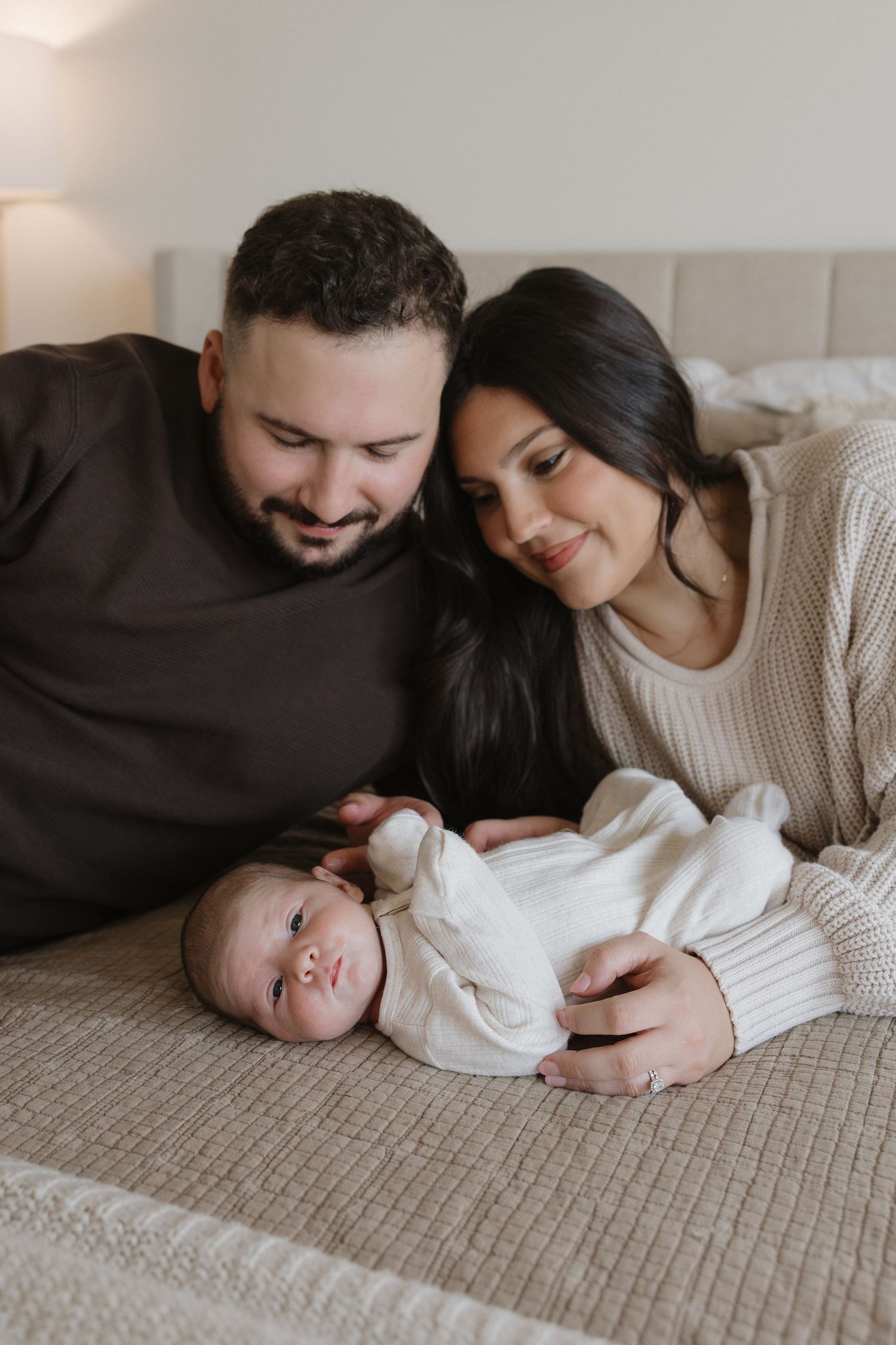 A tender family moment captured on a neutral colored couch with soft natural lighting.