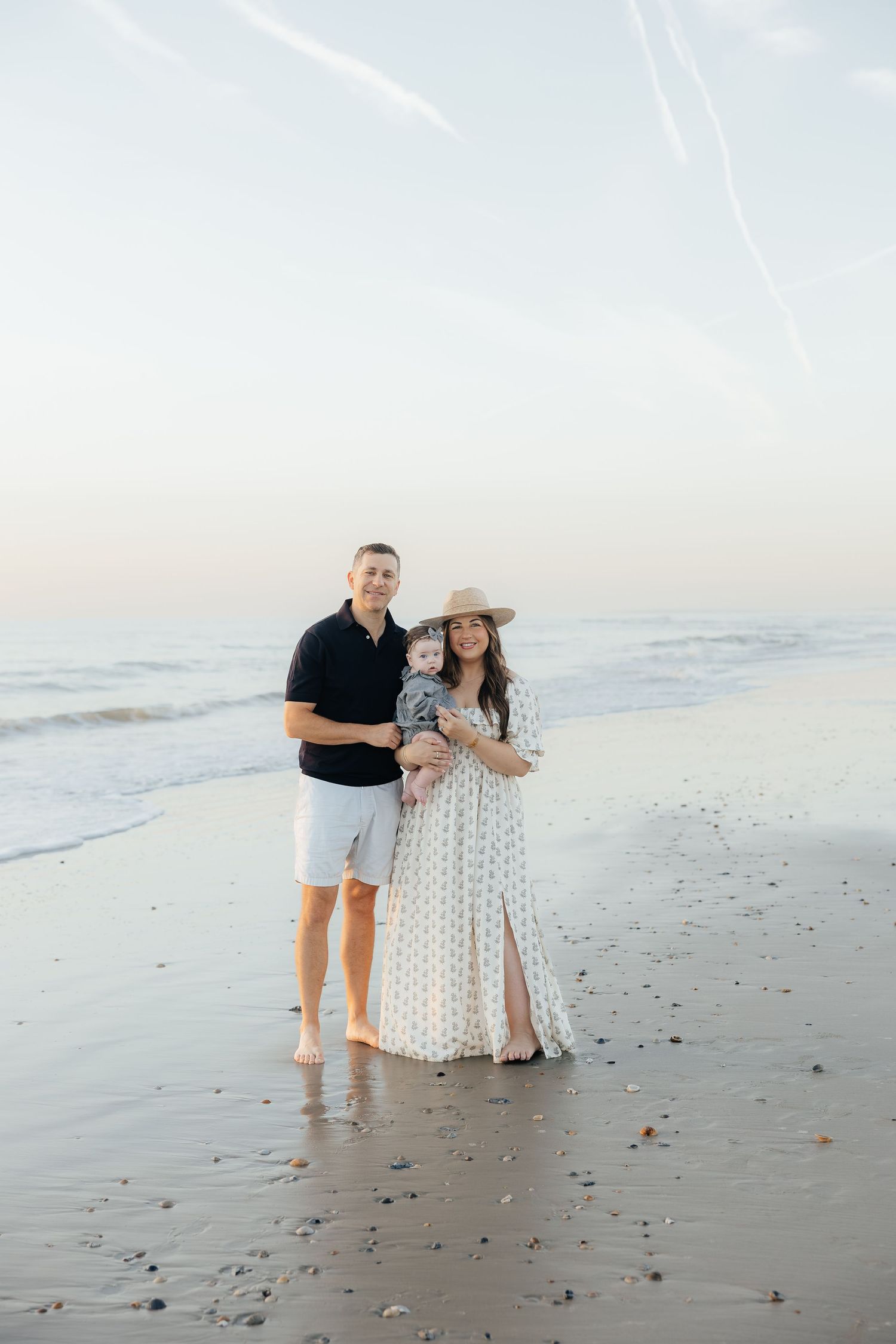 A couple walks along a serene beach at sunset in matching black and white outfits.