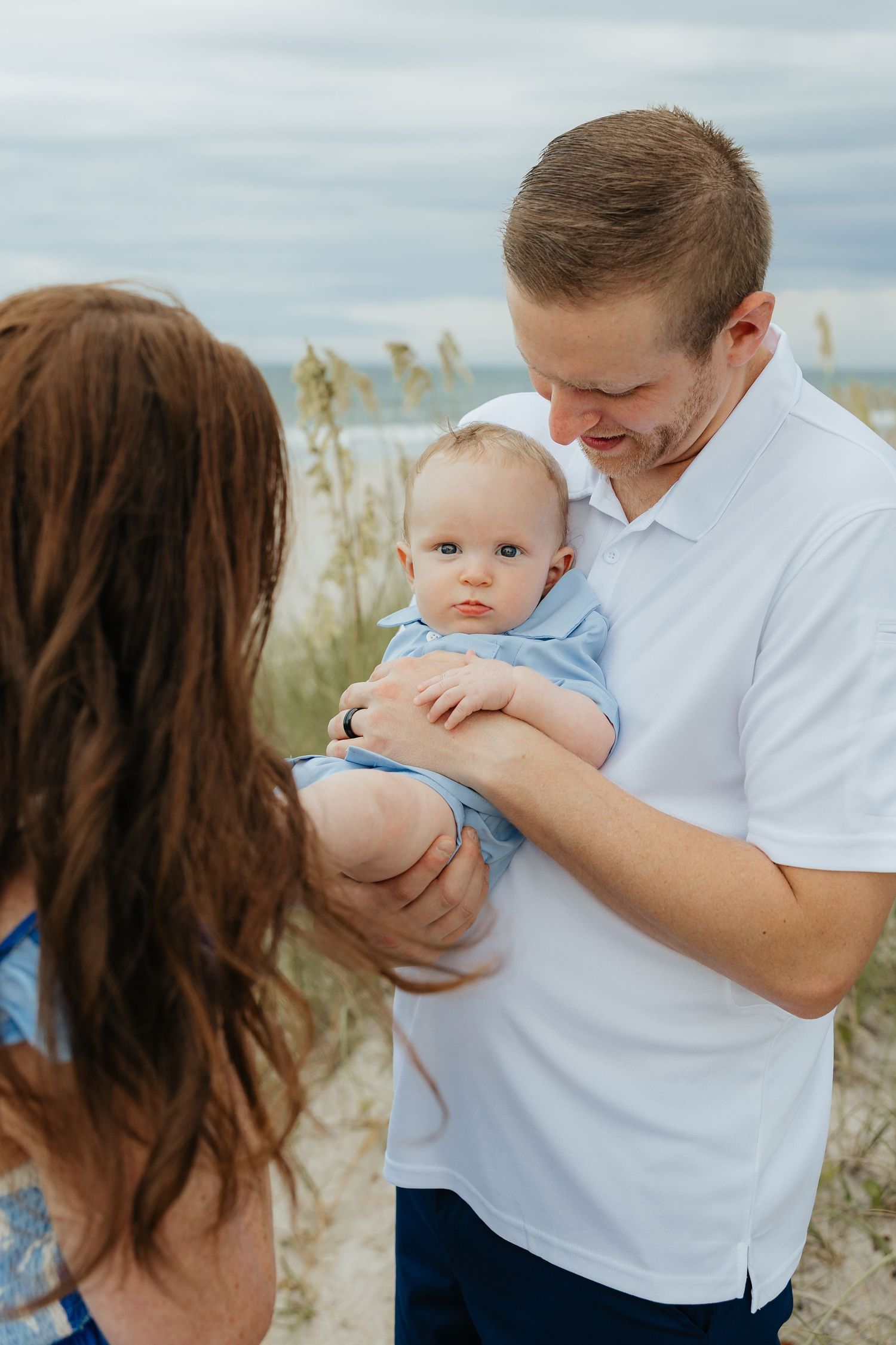 A tender family moment captured among coastal dunes and sea grasses.