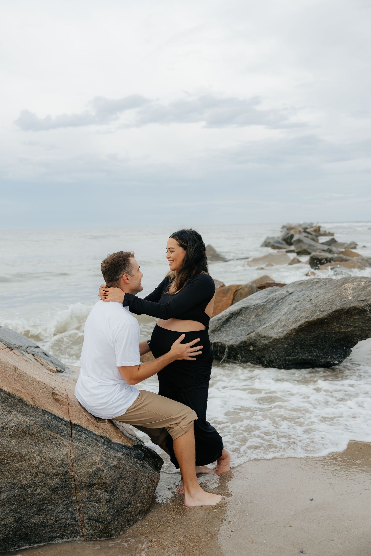 Couple sitting together on large rocks by crashing ocean waves in Fort Clinch State Park.