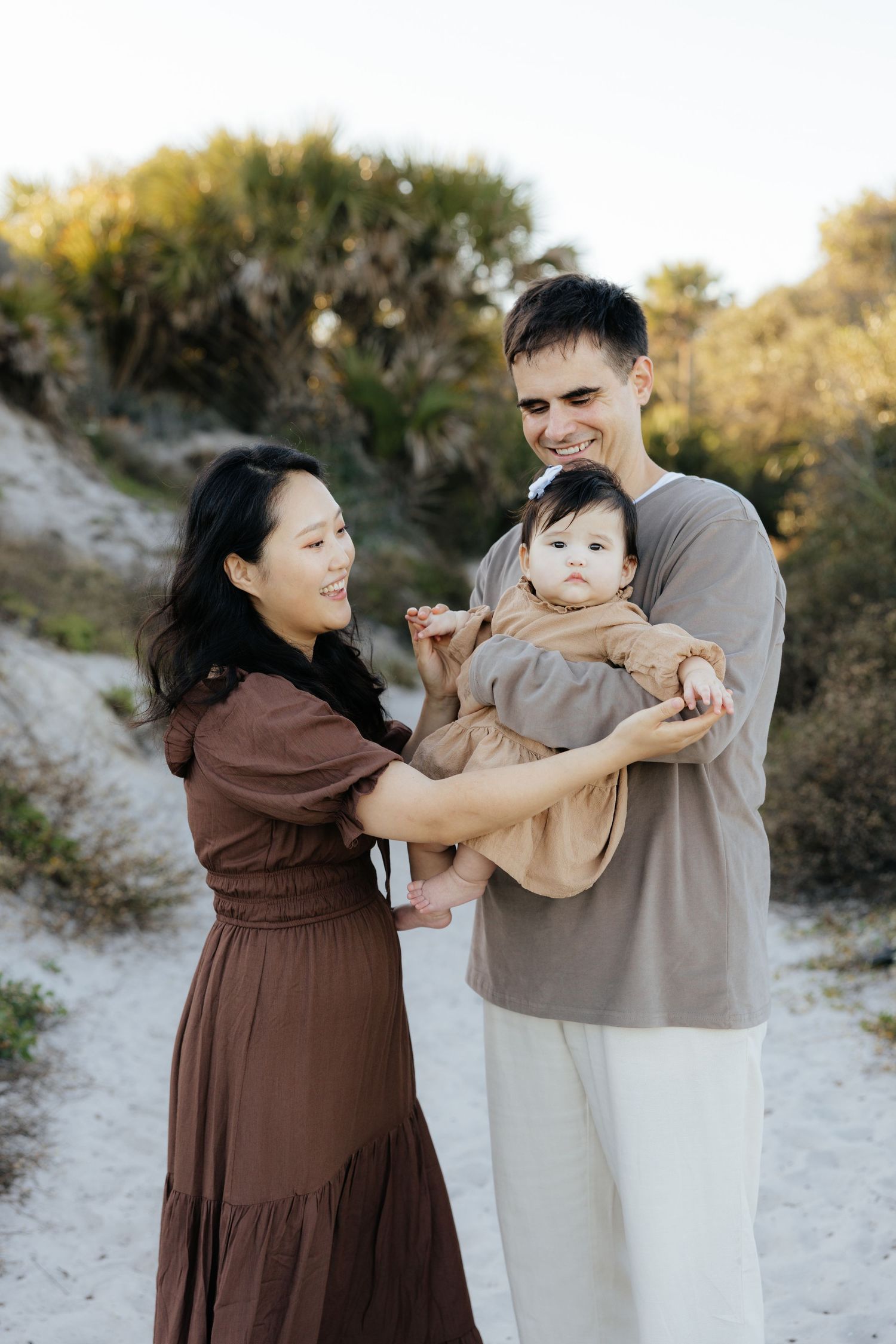 A family shares playful moments together on a sandy beach during golden hour.