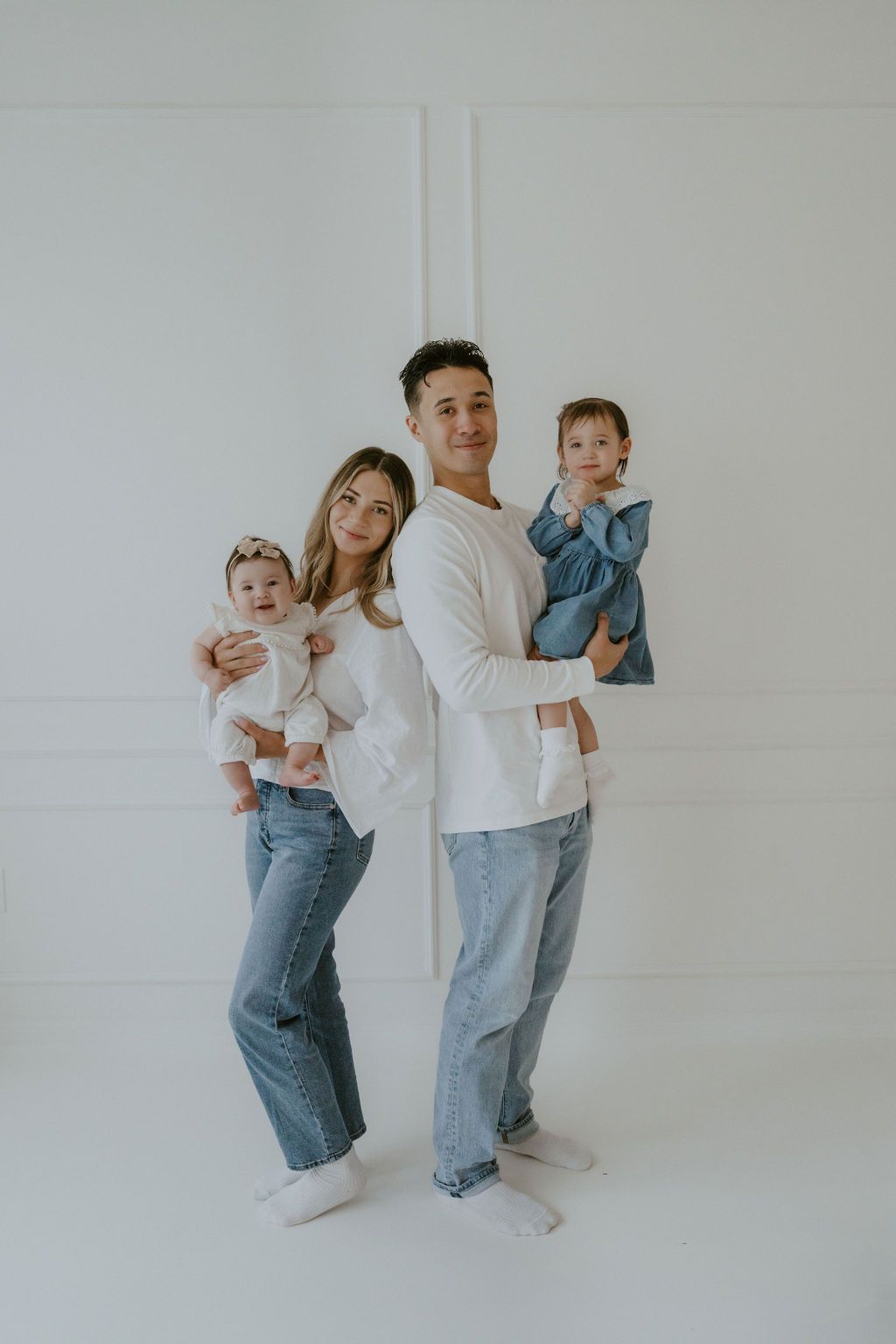 Modern family studio portrait with casual denim outfits against a white background.