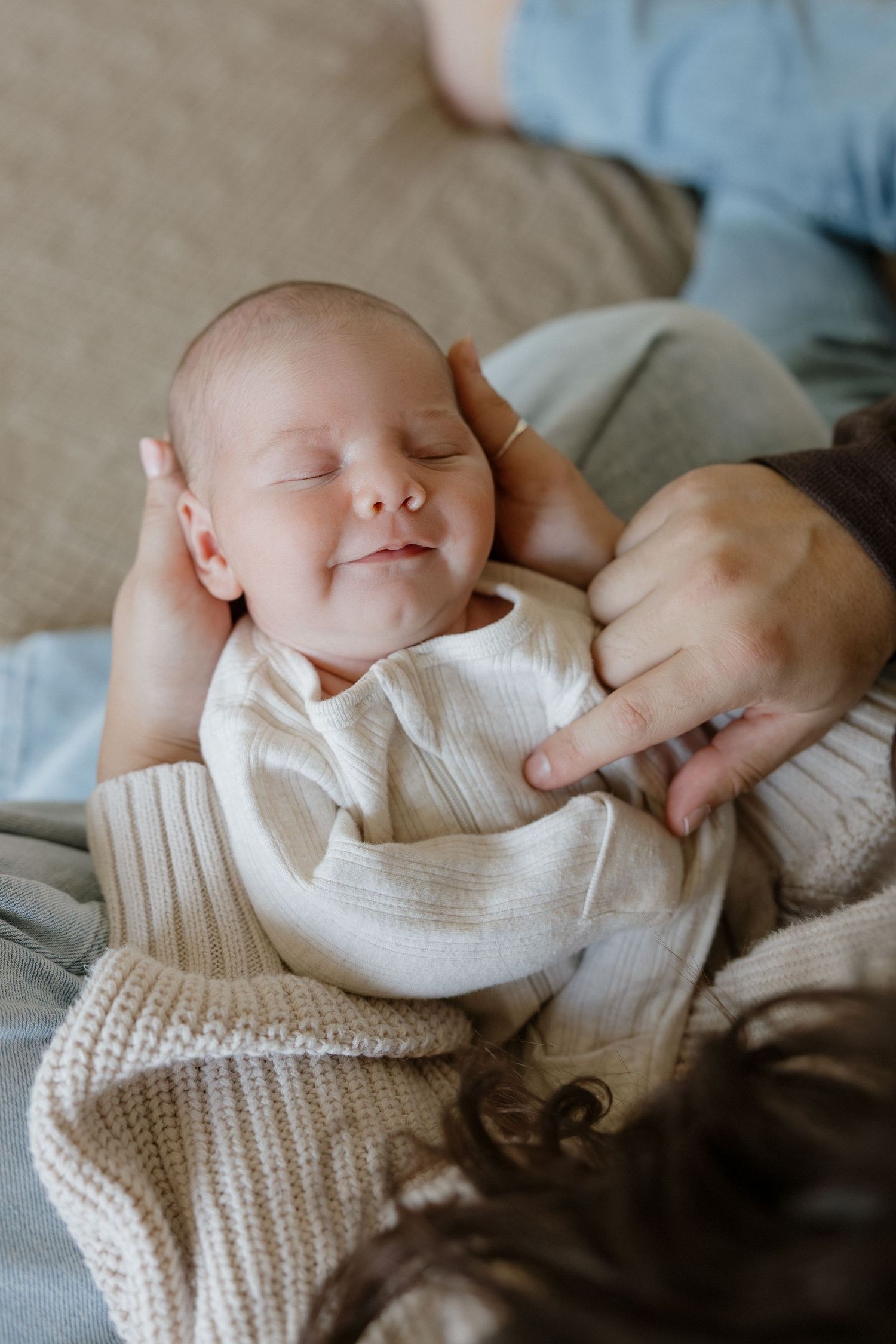 A sleeping newborn wearing a cozy white knit sweater.