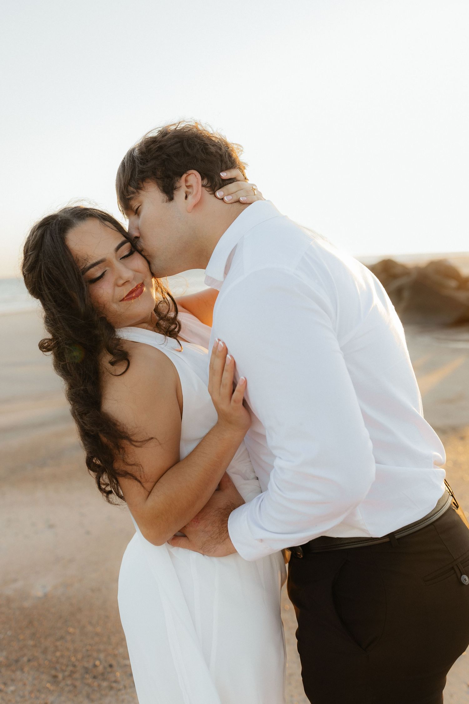 Intimate beach portrait session capturing tender moments at sunset.