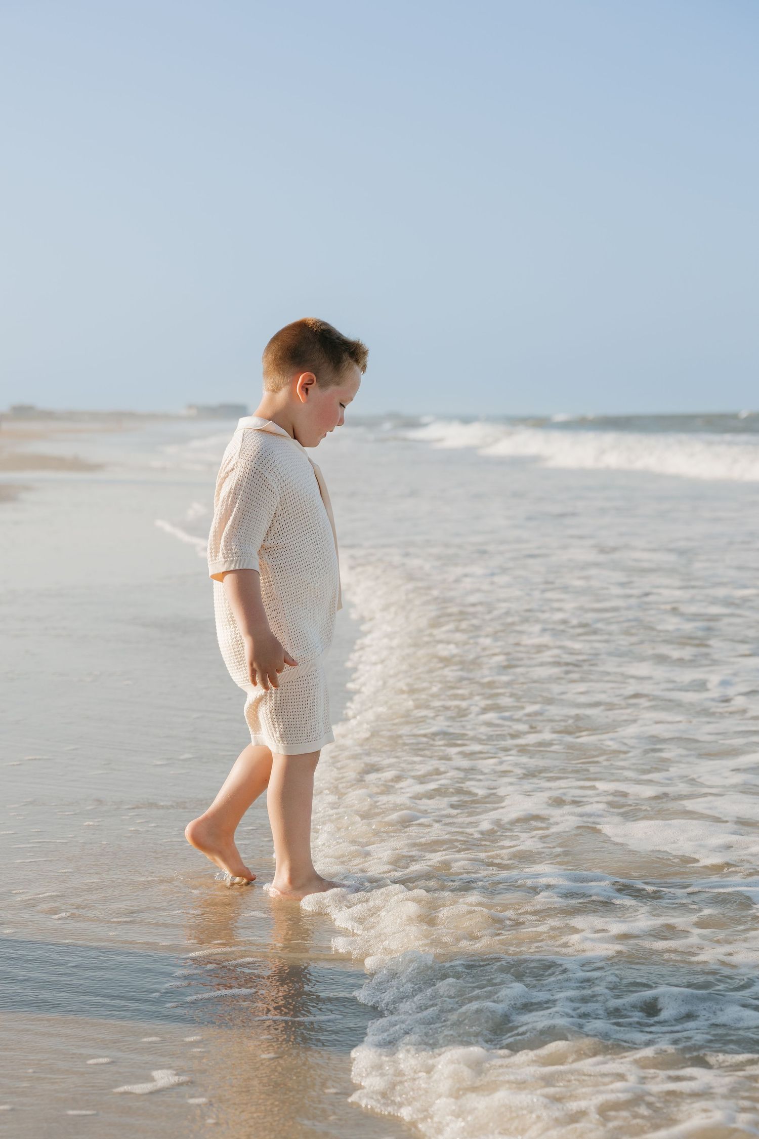 A child stands at the ocean's edge watching waves roll in at Omni Amelia Island Resort & Spa.