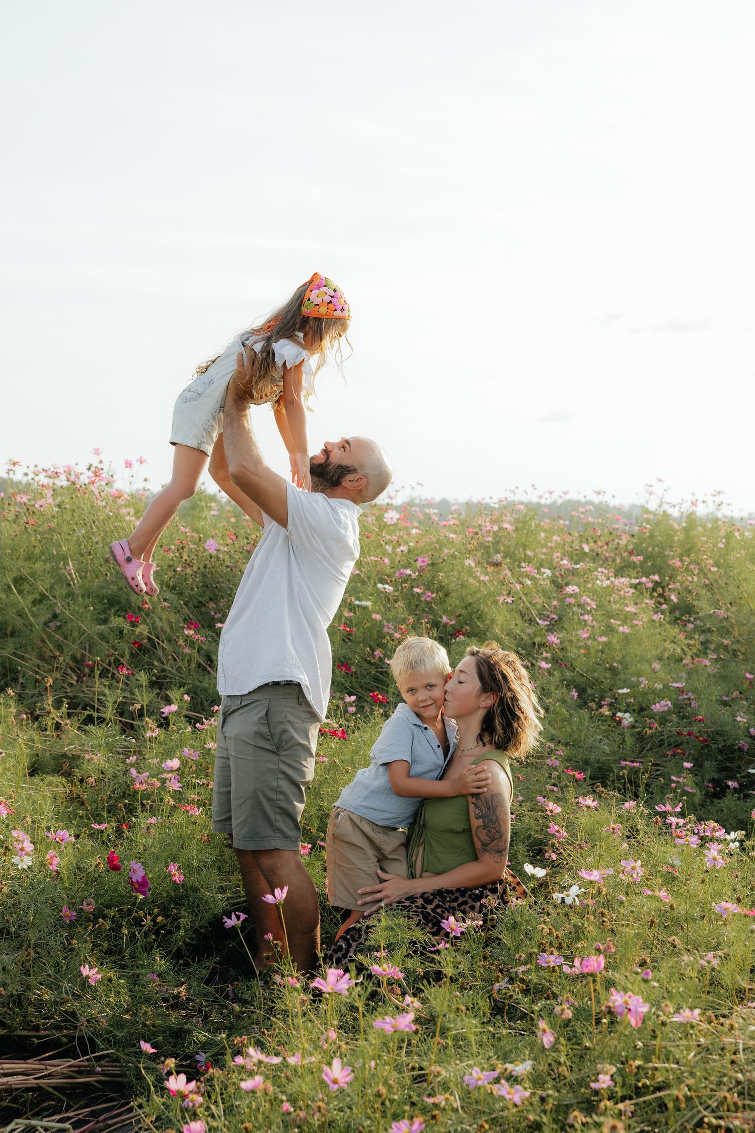 Playful family moment captured in a wildflower meadow during sunset.
