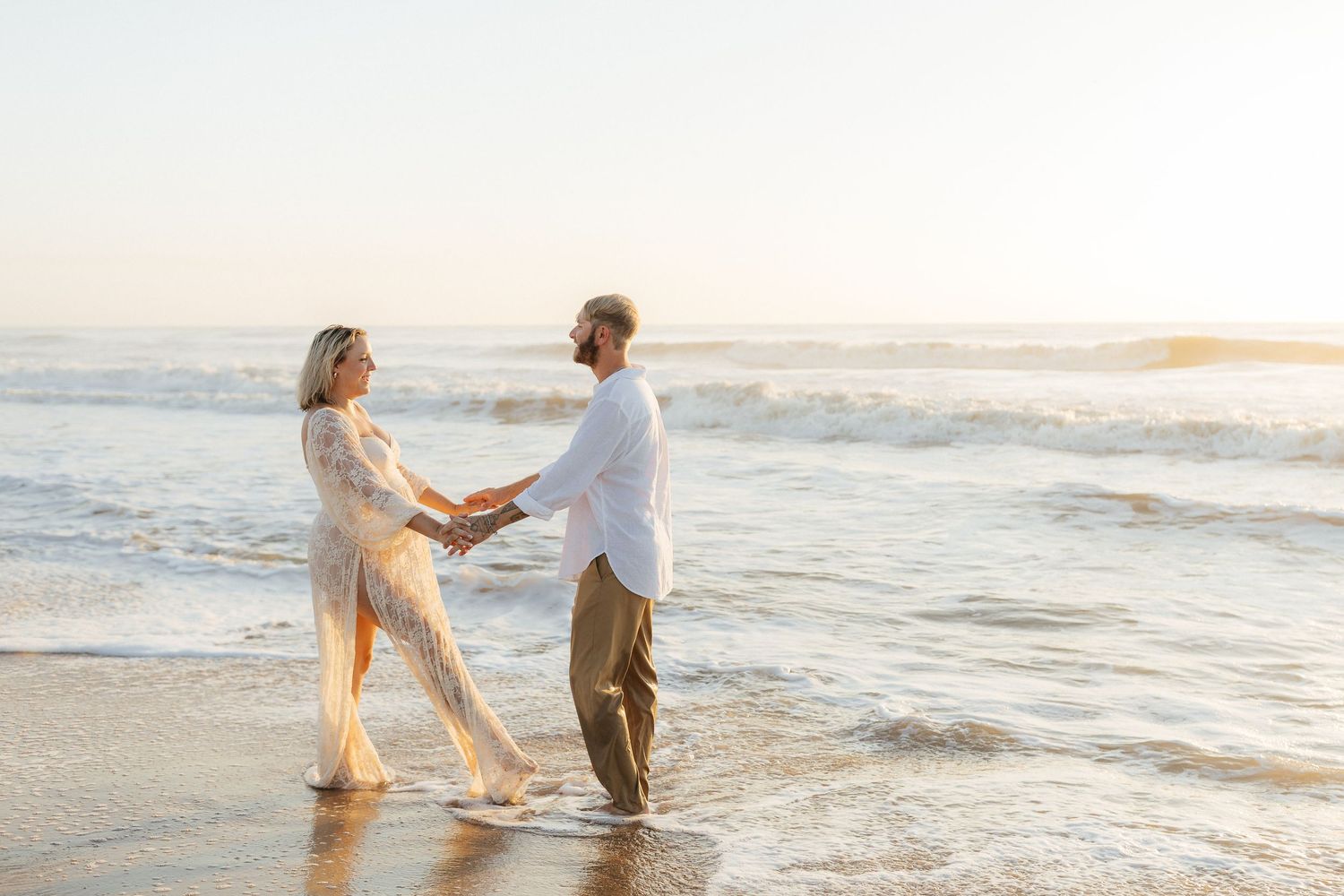Couple dancing together on a beach at sunset with ocean waves in background at Peters Point Beachfront Park.
