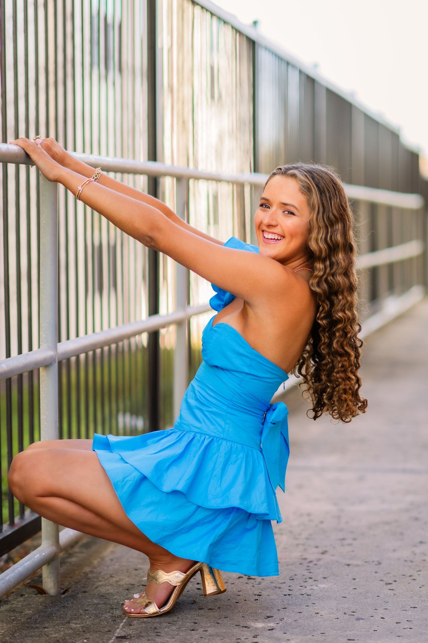Dancer in bright blue dress performs graceful balancing pose sequence against striped wall background.