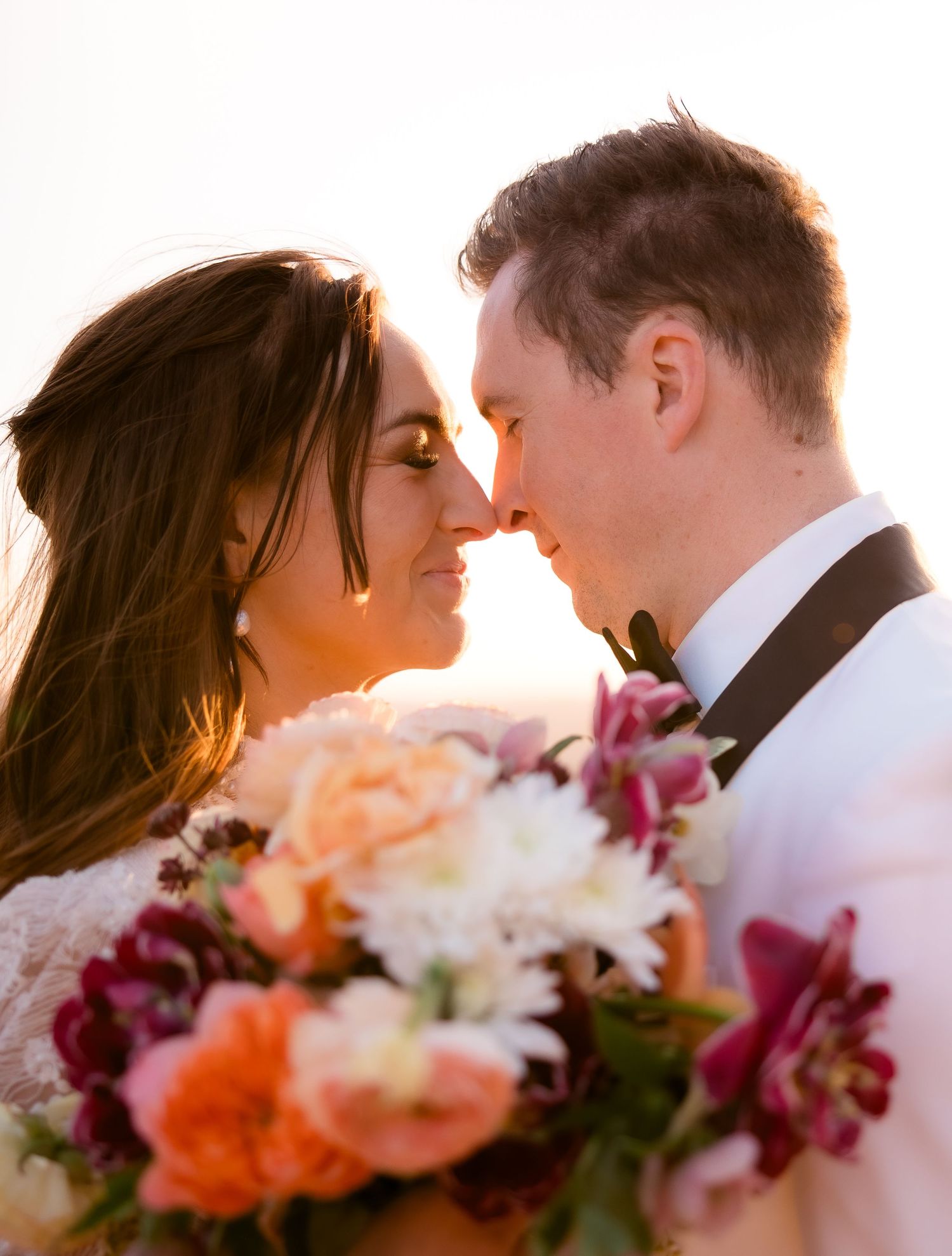 A romantic sunset portrait with colorful floral bouquet in the foreground.